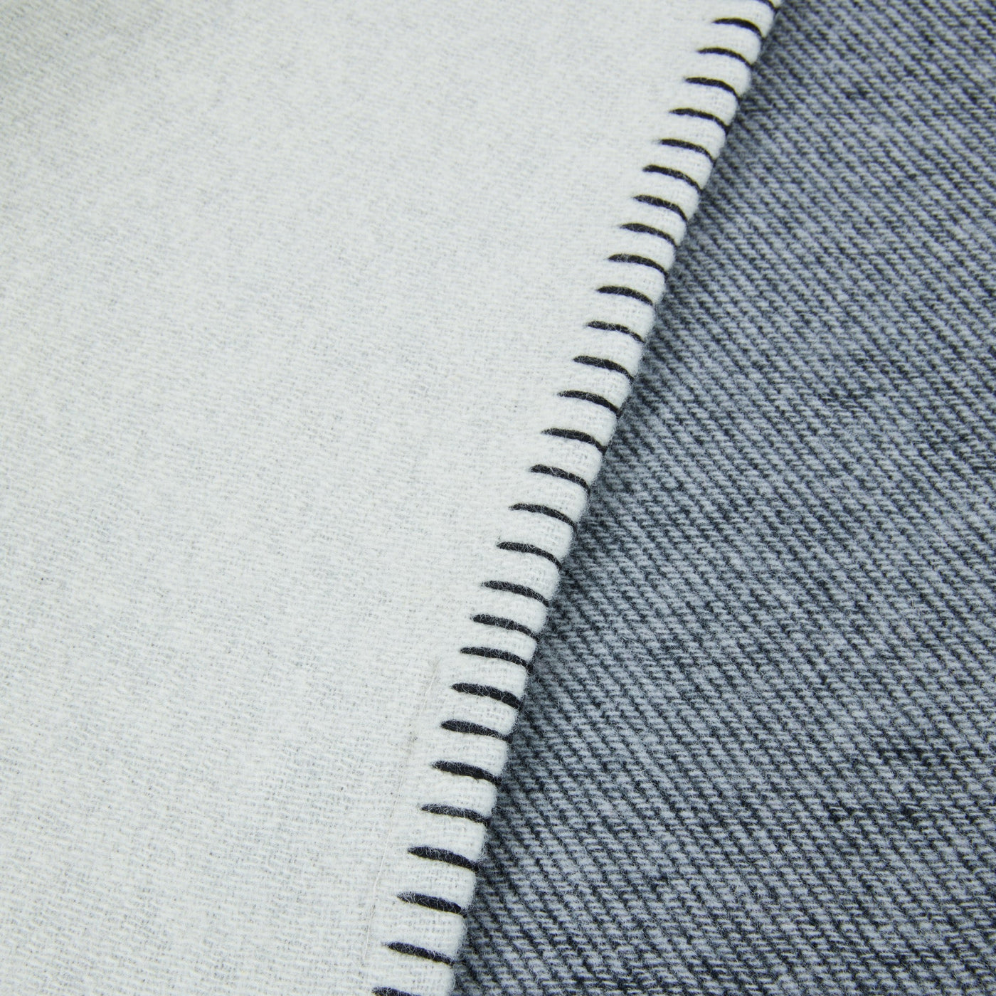 Close-up of navy and ivory wool throw corner with contrast blanket-stitch edge detail.