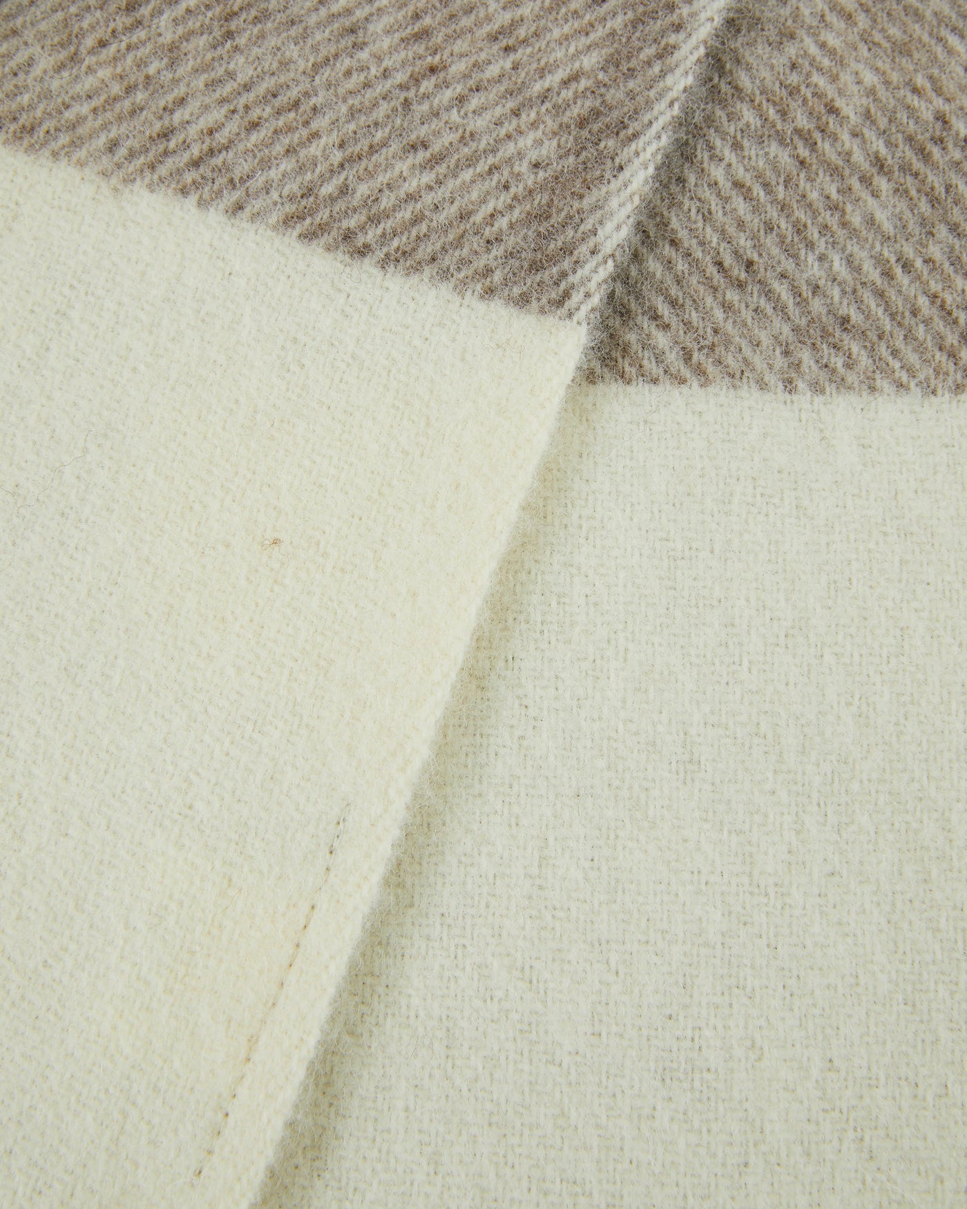 Close-up of Lanerossi Nelson throw corner, ivory wool reverse and taupe herringbone face.