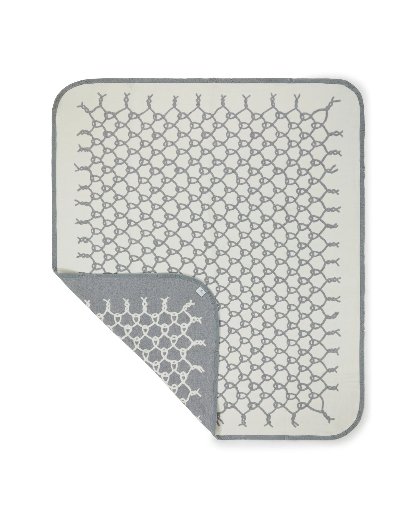 Lanerossi Net blanket corner folded back, revealing grey reverse side of geometric net pattern.