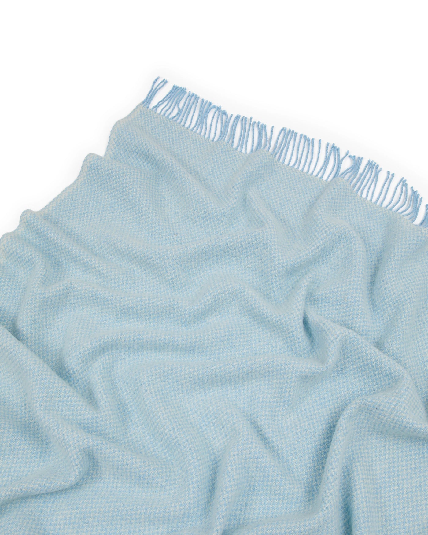 Close-up of Lanerossi Northland throw in sky blue with subtle woven texture and fringe edge.
