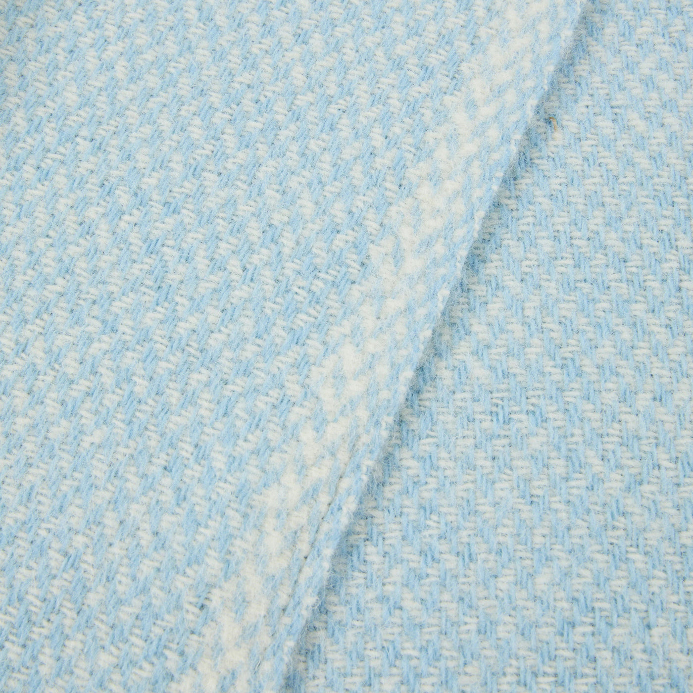 Close-up of Lanerossi Northland throw's sky blue and ivory basketweave texture, folded edge visible.