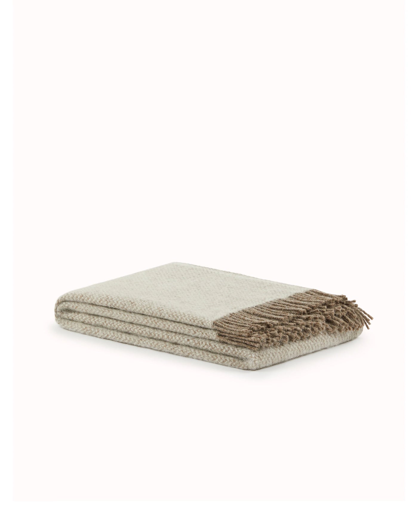 Folded Lanerossi Northland throw in ivory with taupe herringbone weave and fringe trim.