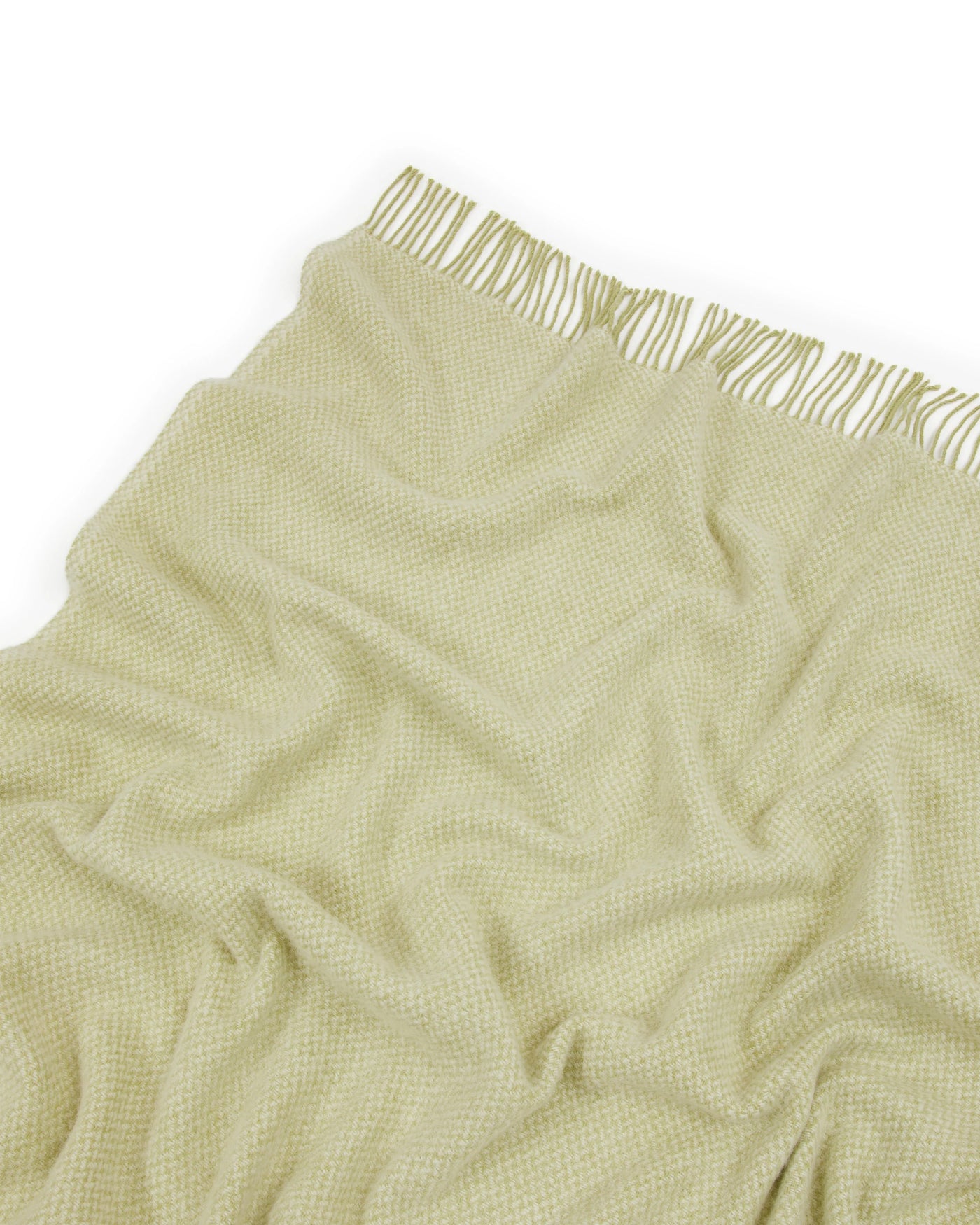 Close-up of Northland throw fringe edge in sage green woven texture against white background.