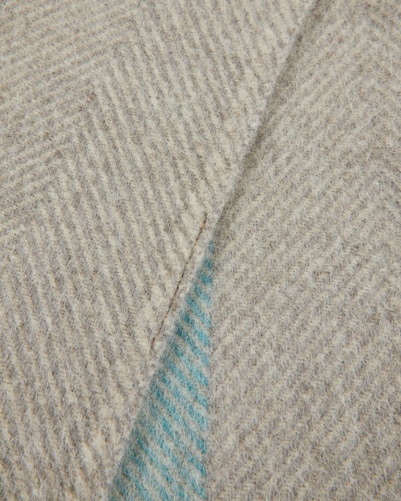 Close-up of Lanerossi Opua throw corner, revealing aqua herringbone reverse beneath oatmeal face.