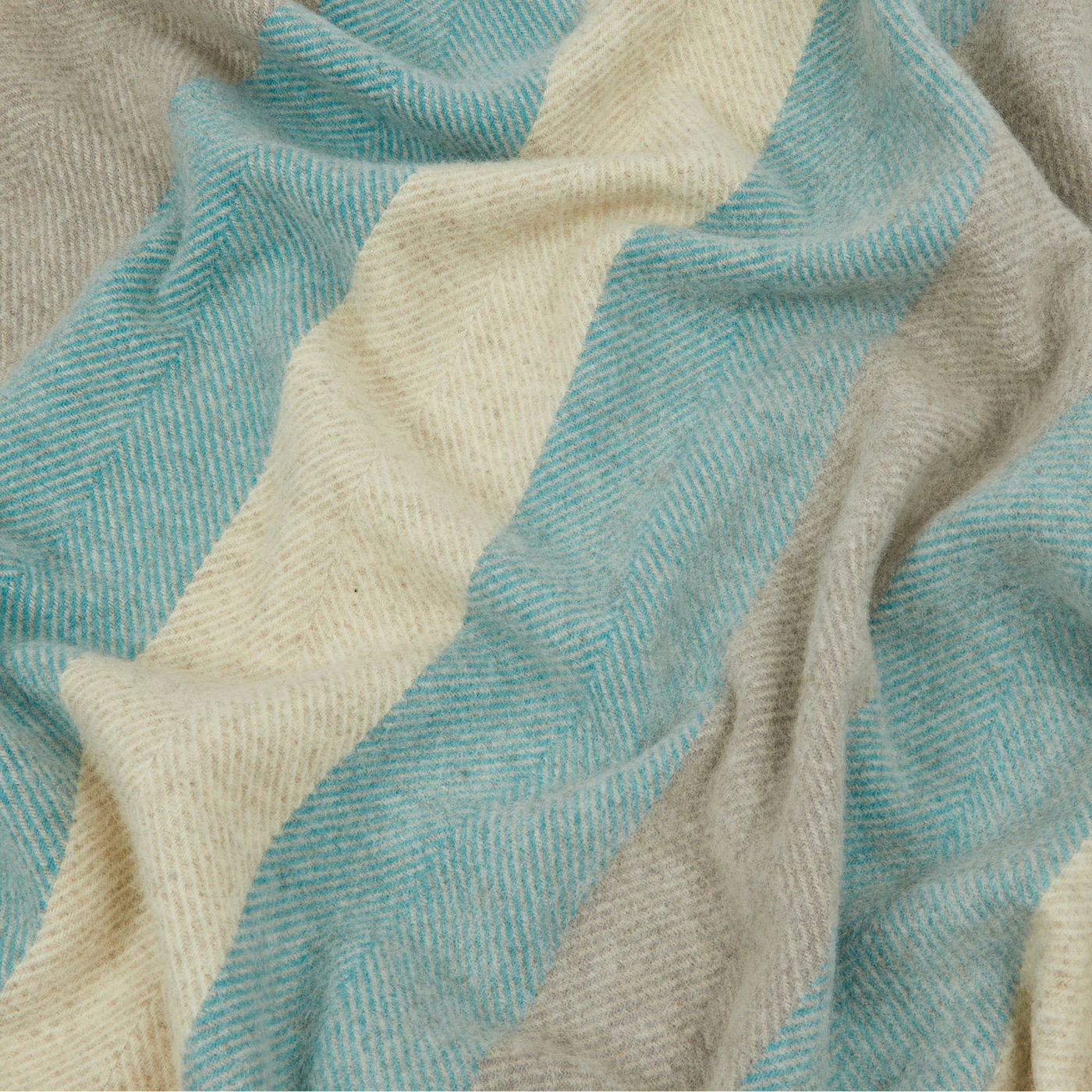 Close-up of draped Opua throw with aqua and ivory herringbone stripes.