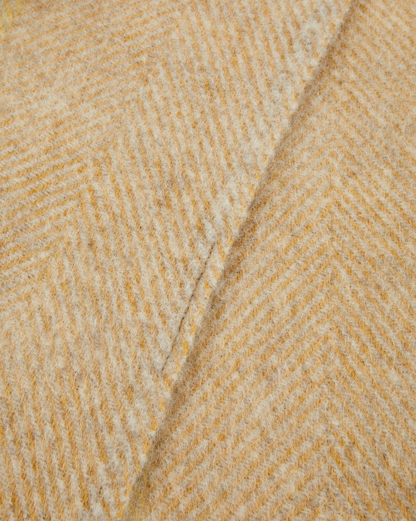 Close-up of Lanerossi Opua throw's honey herringbone wool weave with folded edge detail.