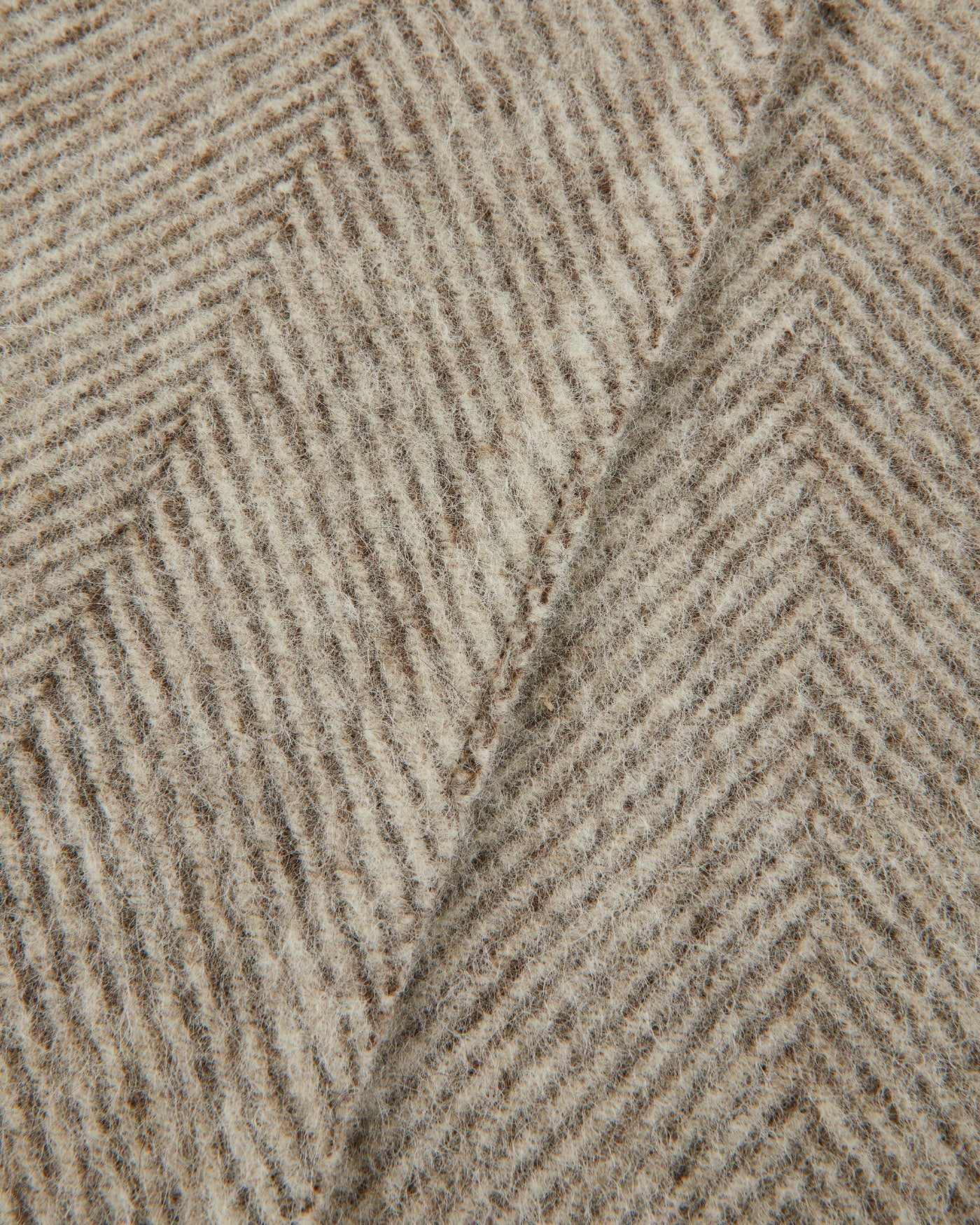 Close-up of Lanerossi Opua throw's oatmeal herringbone weave texture with folded edge detail.