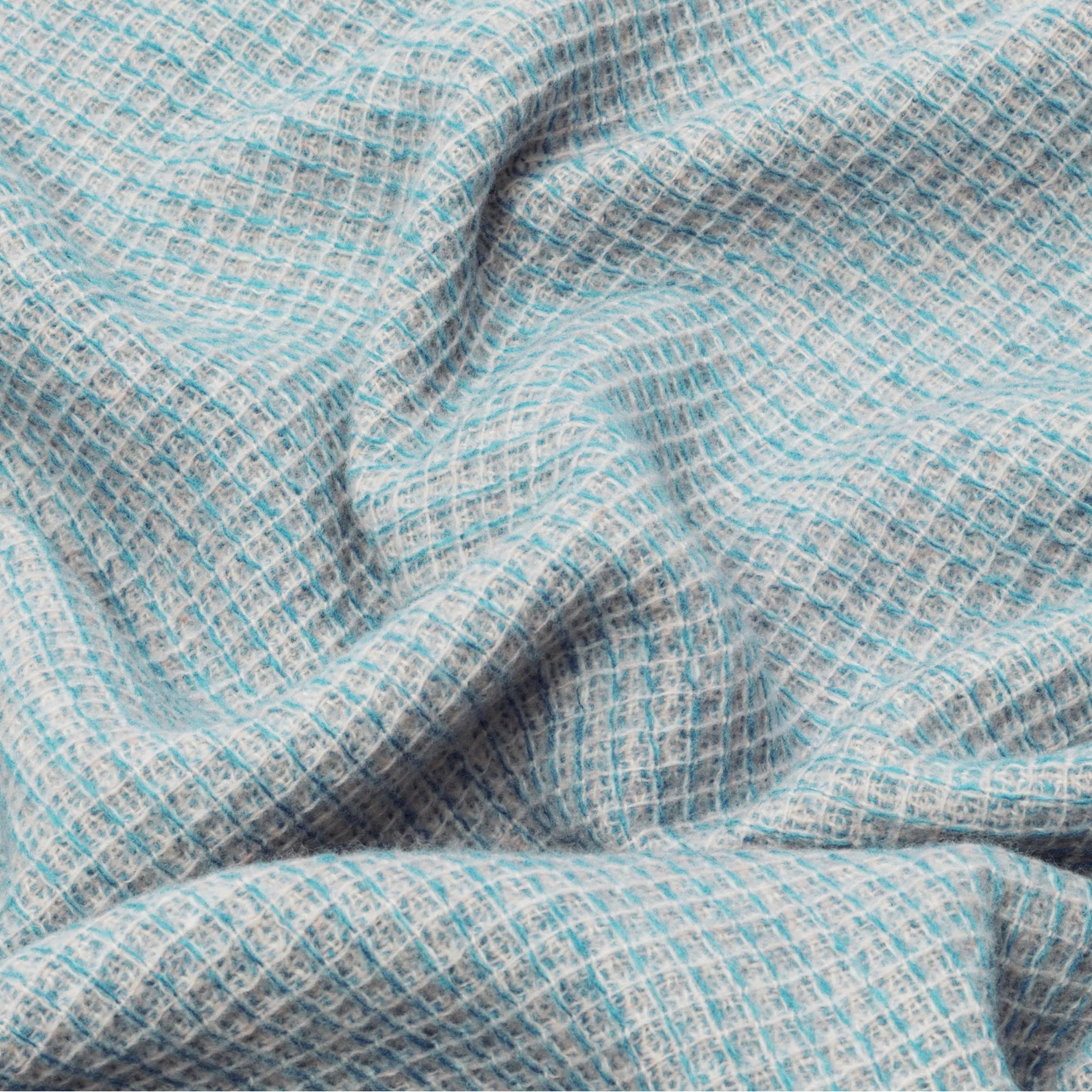 Close-up of draped aqua and ivory woven throw with textured grid pattern.