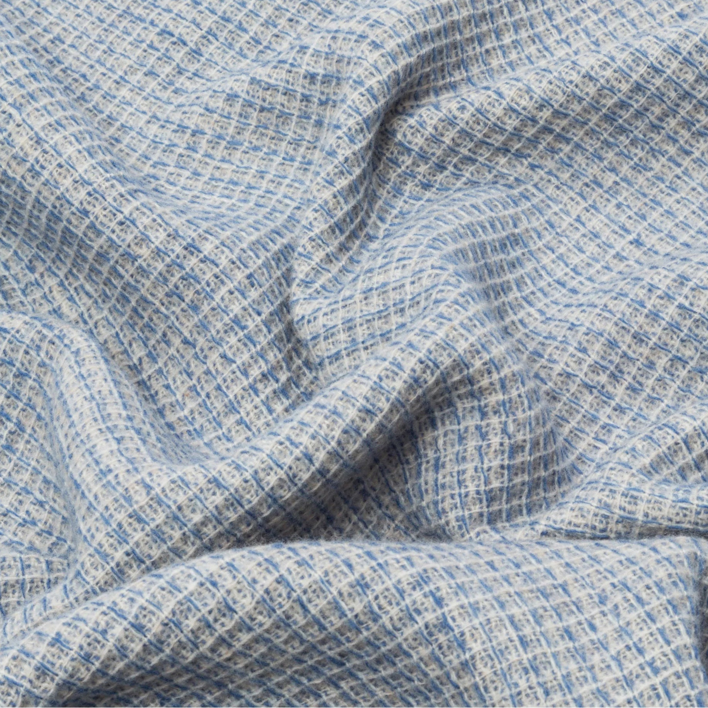 Close-up of draped Lanerossi Rossi Moon throw showing blue and ivory open-weave texture.