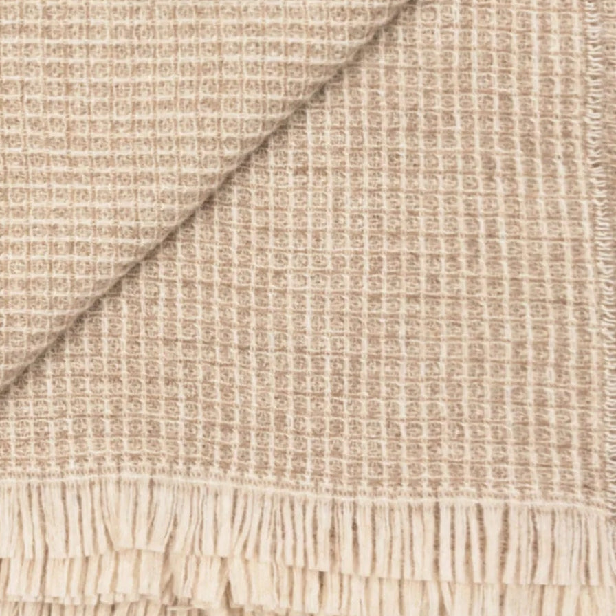 Close-up of Lanerossi Rossi Moon throw's waffle-weave texture in sand and ivory with fringe hem.