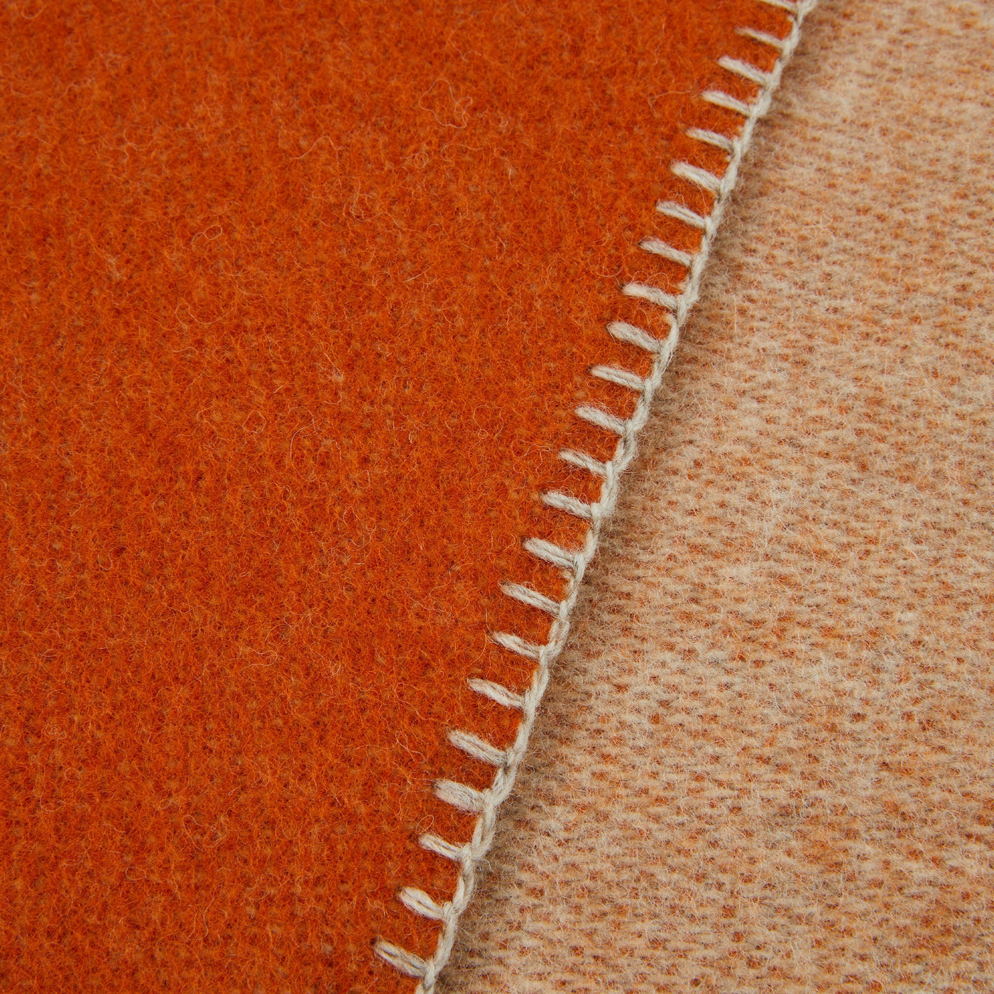 Close-up of ivory blanket-stitch edge joining rust and sand wool sides of Lanerossi Southland throw.