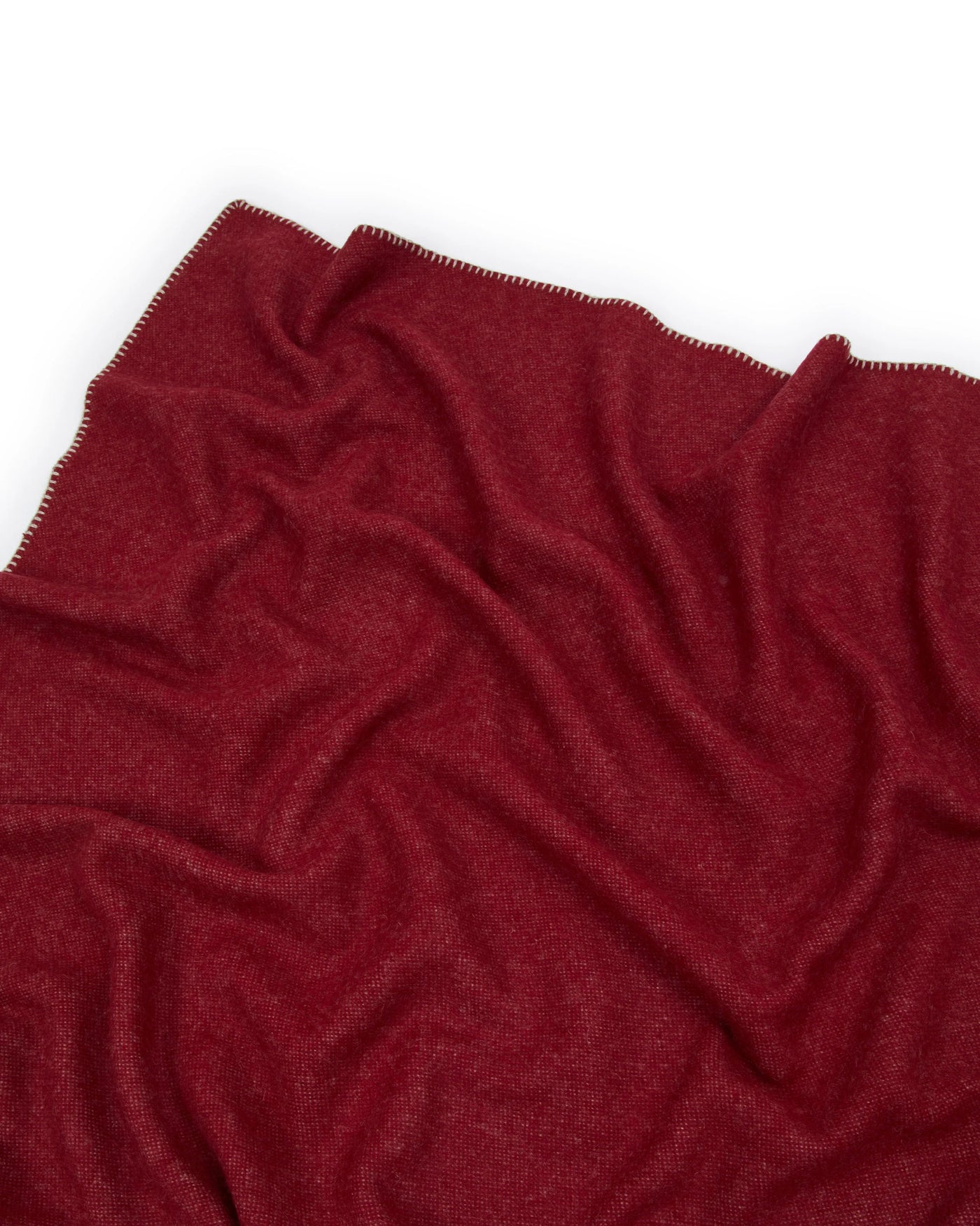 Close-up of draped crimson Lanerossi Southland throw, showing blanket-stitched edge detail.