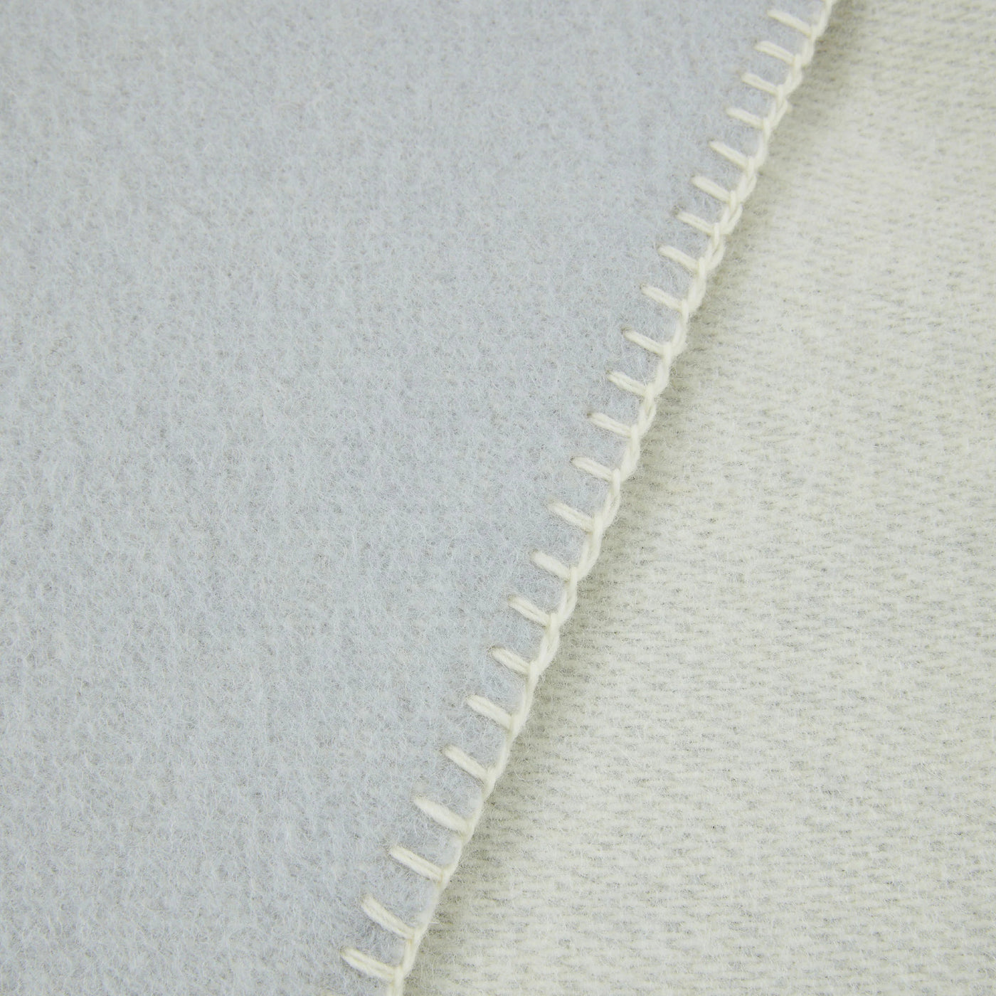 Close-up of Lanerossi Southland throw's blanket-stitched ivory edge, contrasting textures on both sides.
