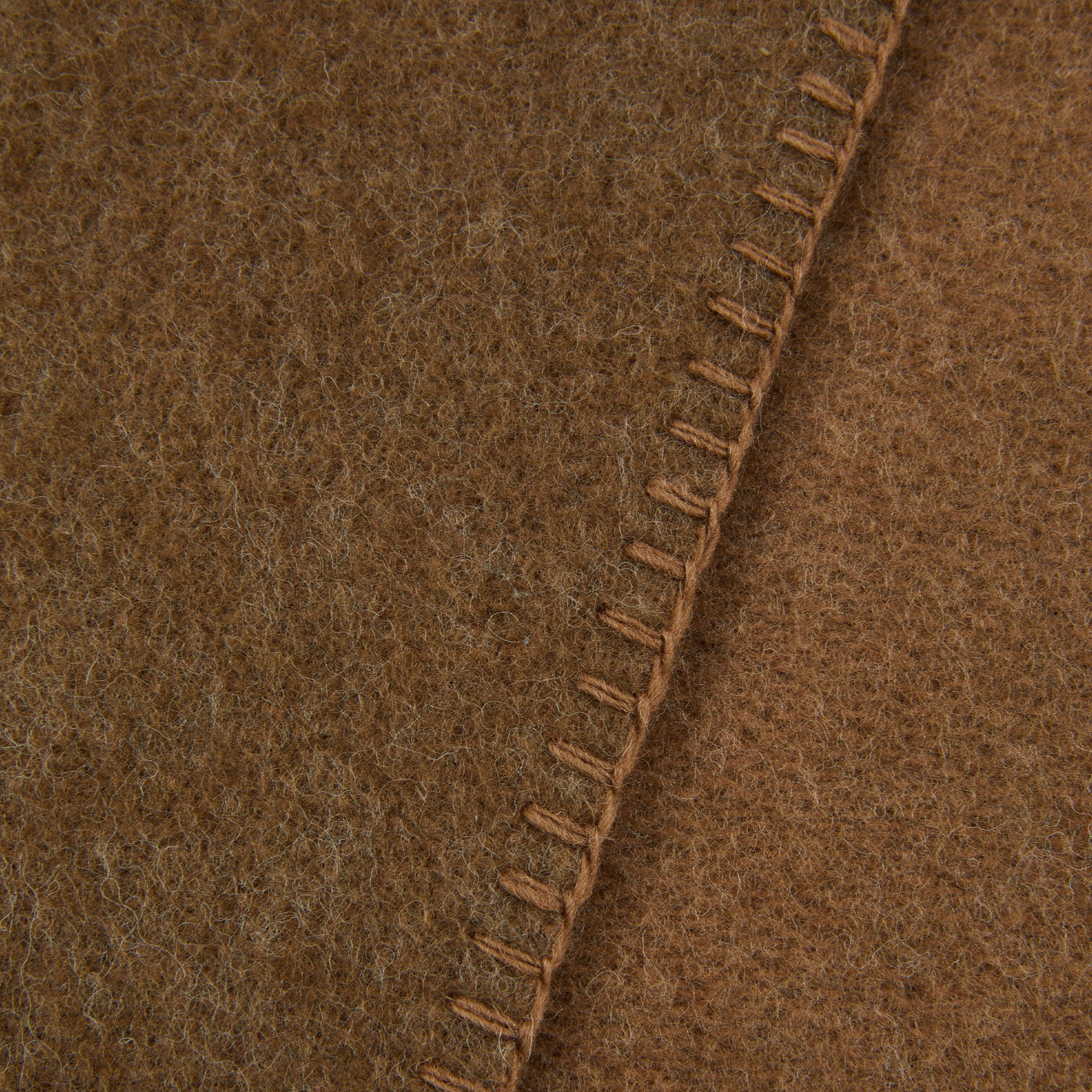 Close-up of Lanerossi Southland throw's whipstitch edge in camel wool felt.