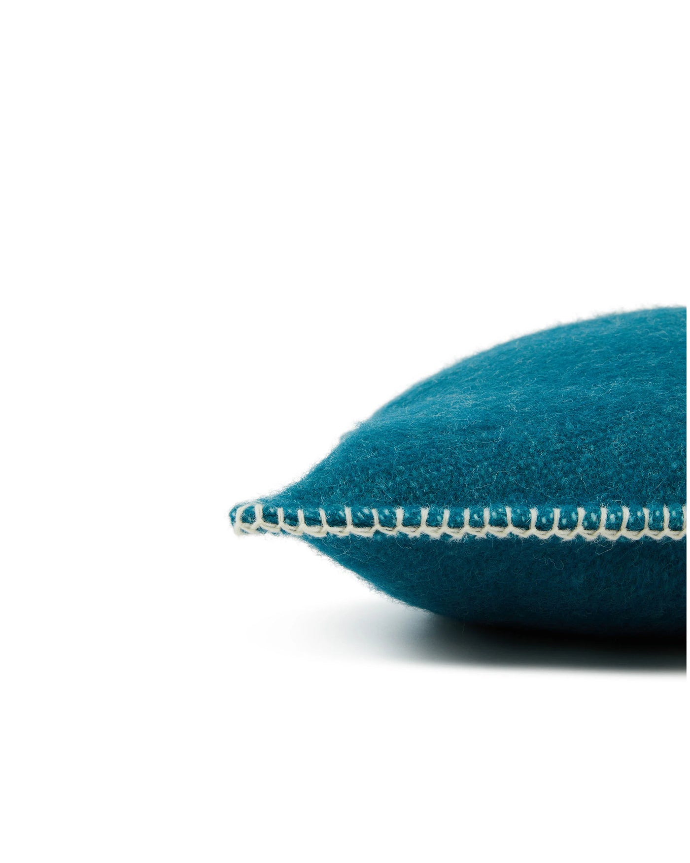 Close-up of Lanerossi Southland cushion edge, teal wool with ivory blanket-stitch trim detail.