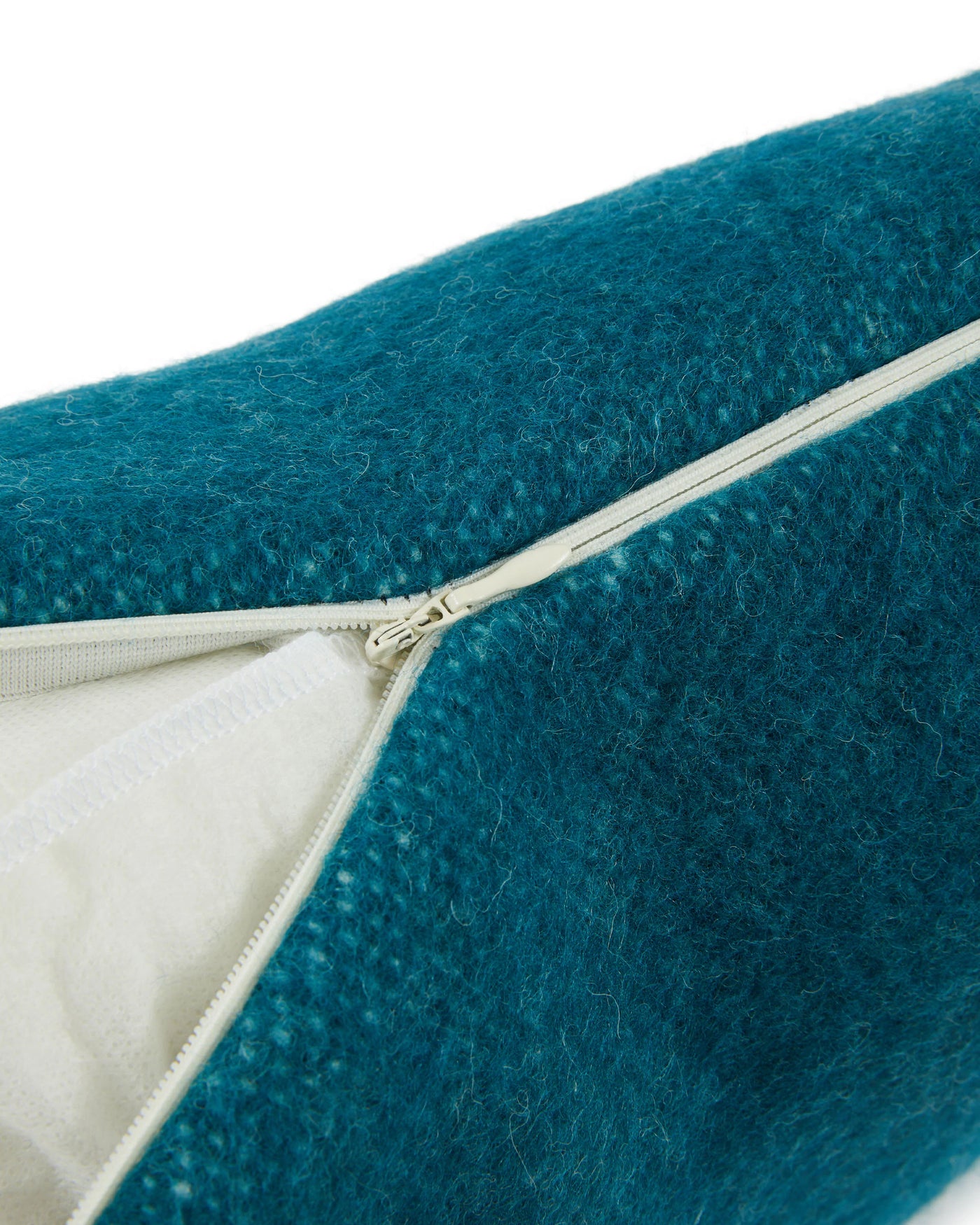 Close-up of Lanerossi Southland cushion zipper closure, teal wool texture with ivory lining.