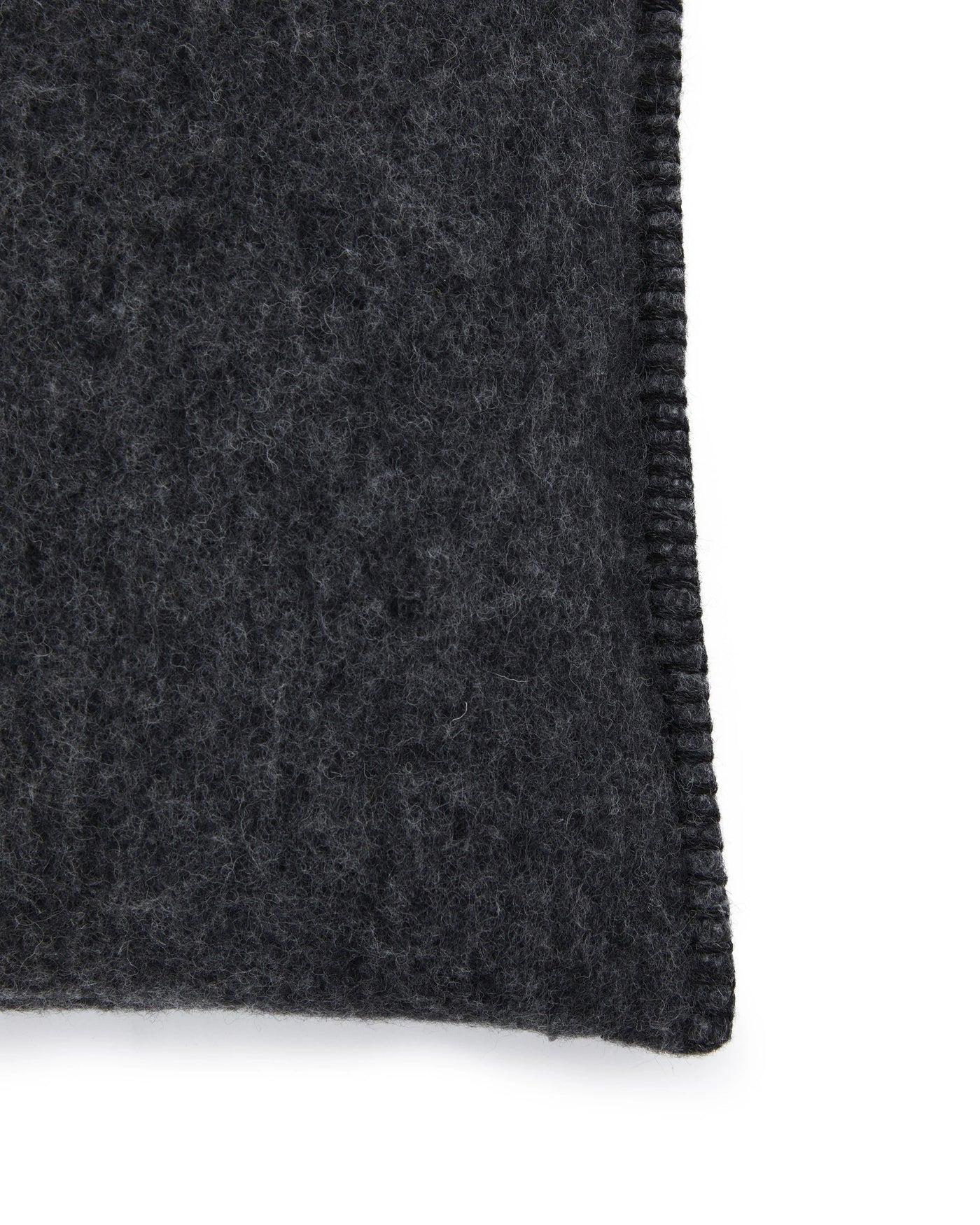 Close-up of charcoal wool cushion corner showing blanket-stitch edge detail.