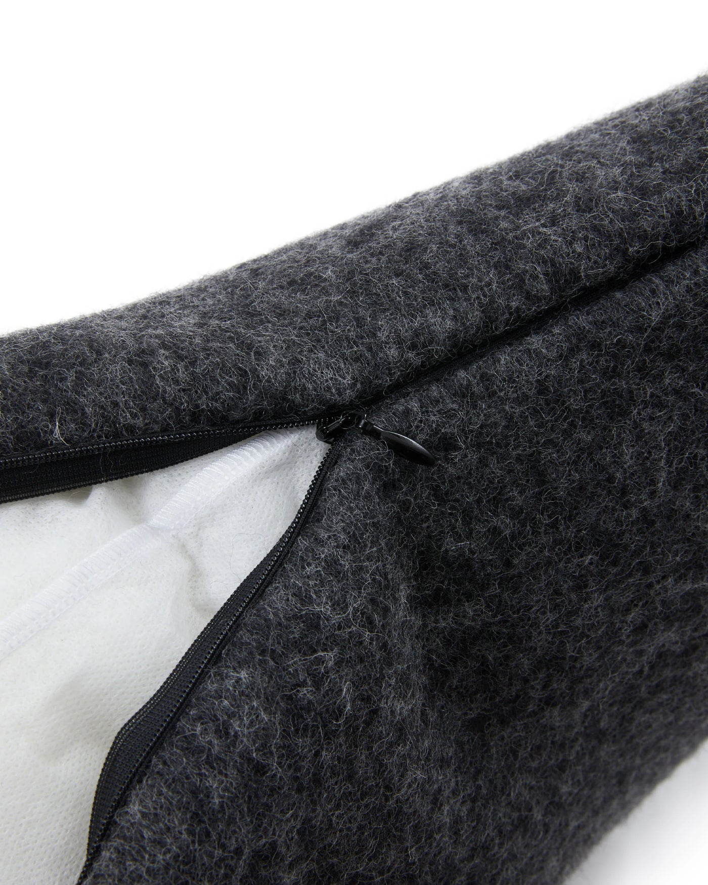 Close-up of charcoal wool cushion cover zipper closure, white interior visible.
