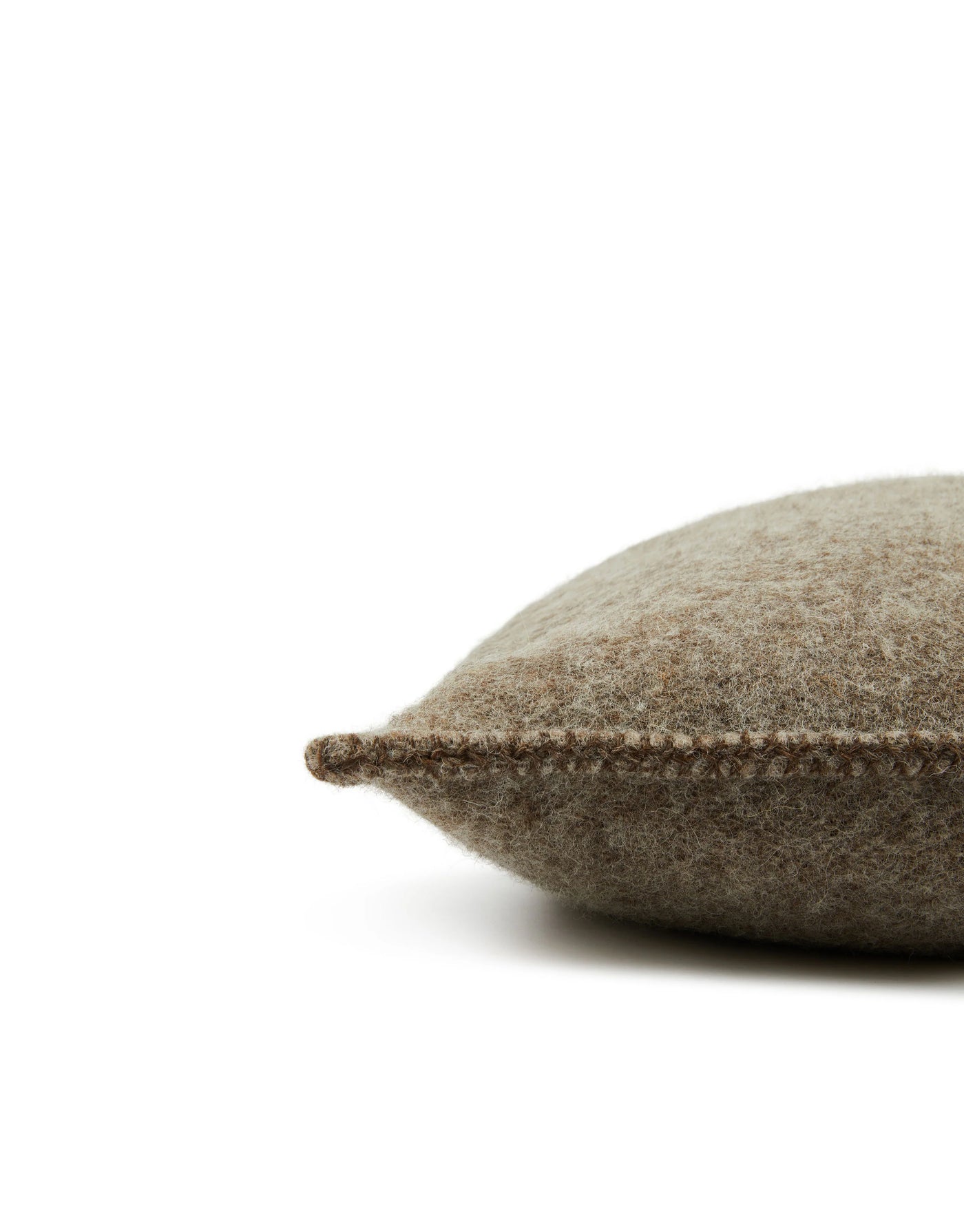 Side profile view of a taupe felted wool cushion showing whipstitch edge detail.