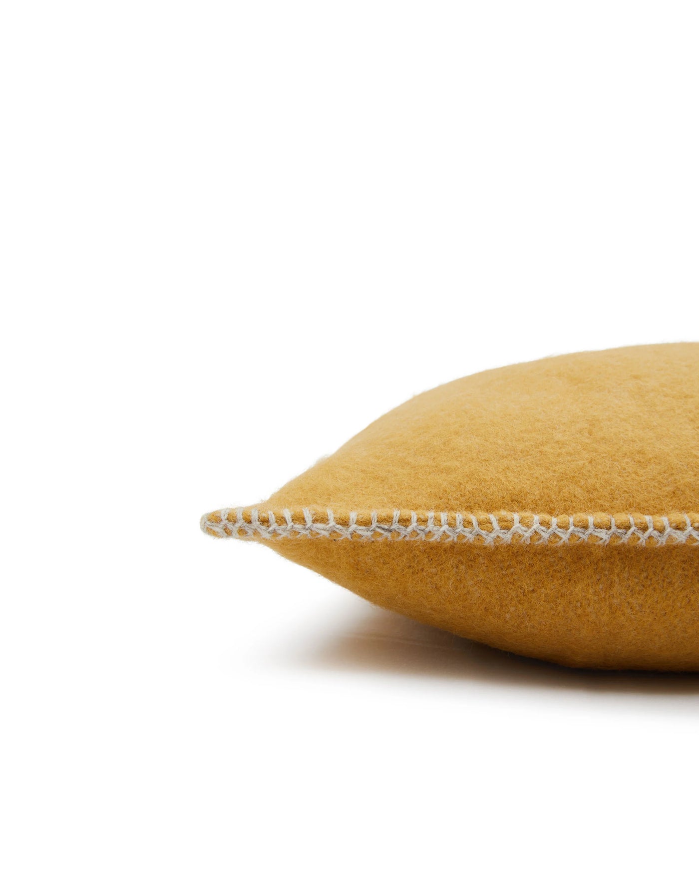 Close-up of Lanerossi Southland cushion edge in mustard wool with ivory blanket stitch trim.