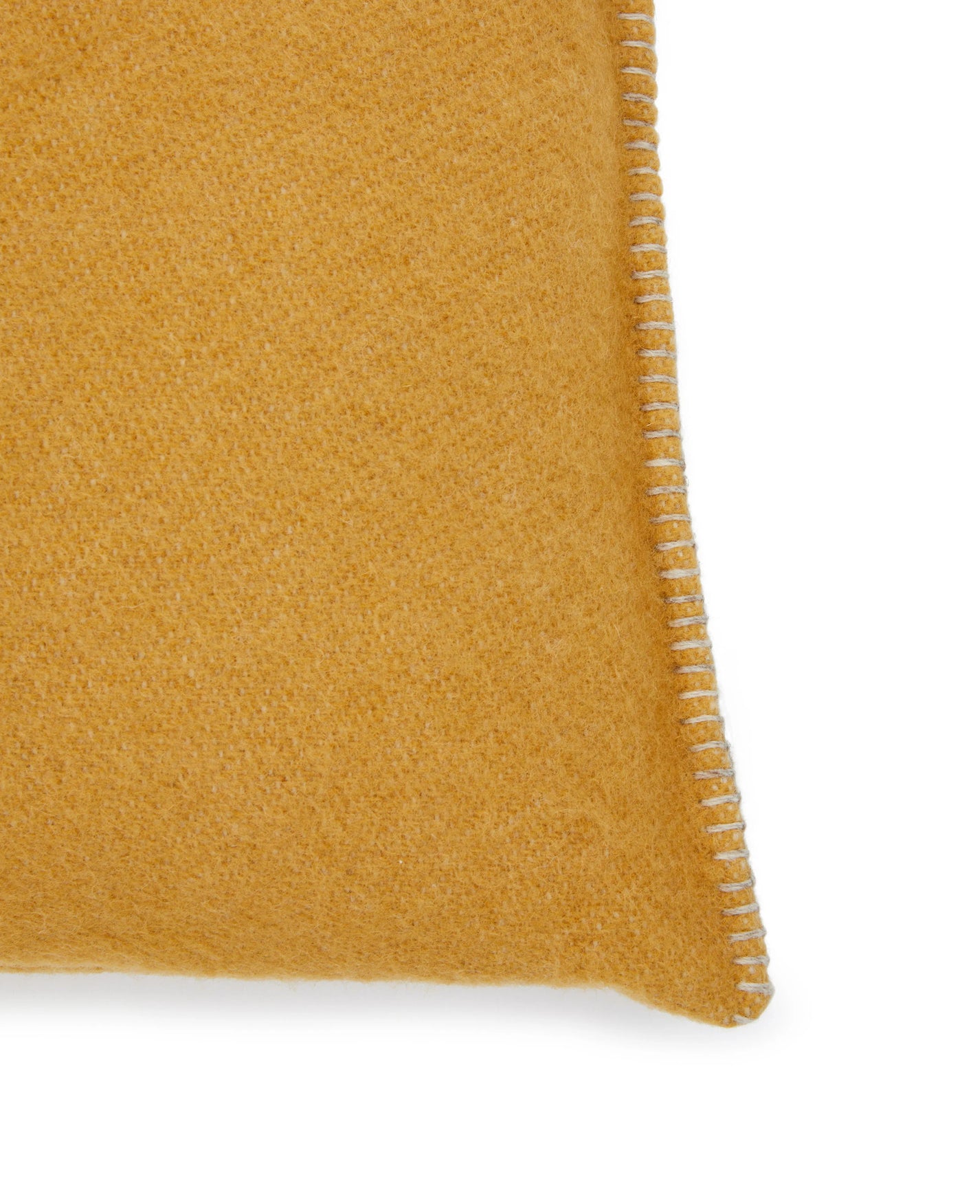 Close-up of Lanerossi Southland cushion corner in saffron wool with whipstitch trim detail.