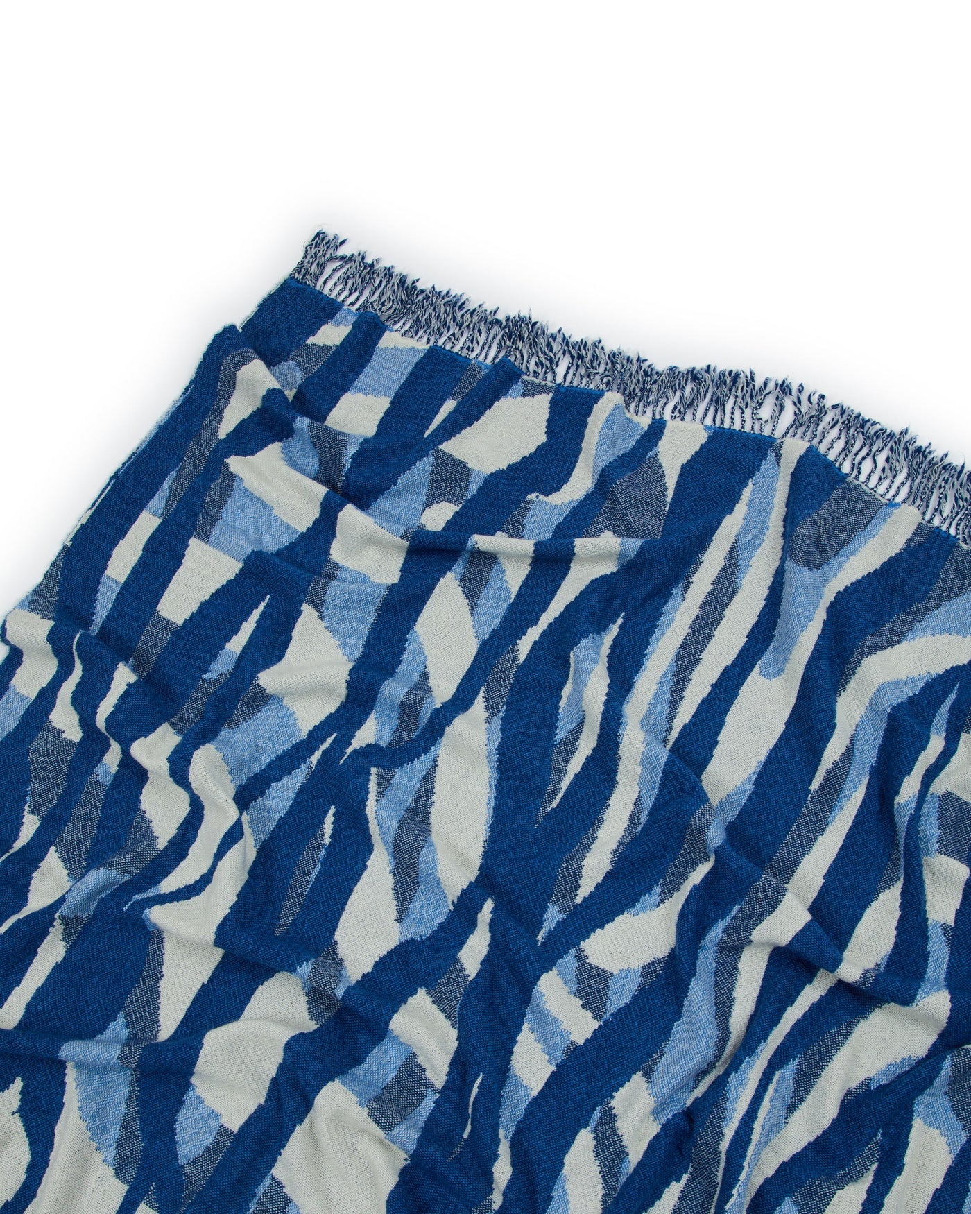 Close-up of Lanerossi Struttura throw corner, showing cobalt and ivory abstract wave pattern with fringe edge.