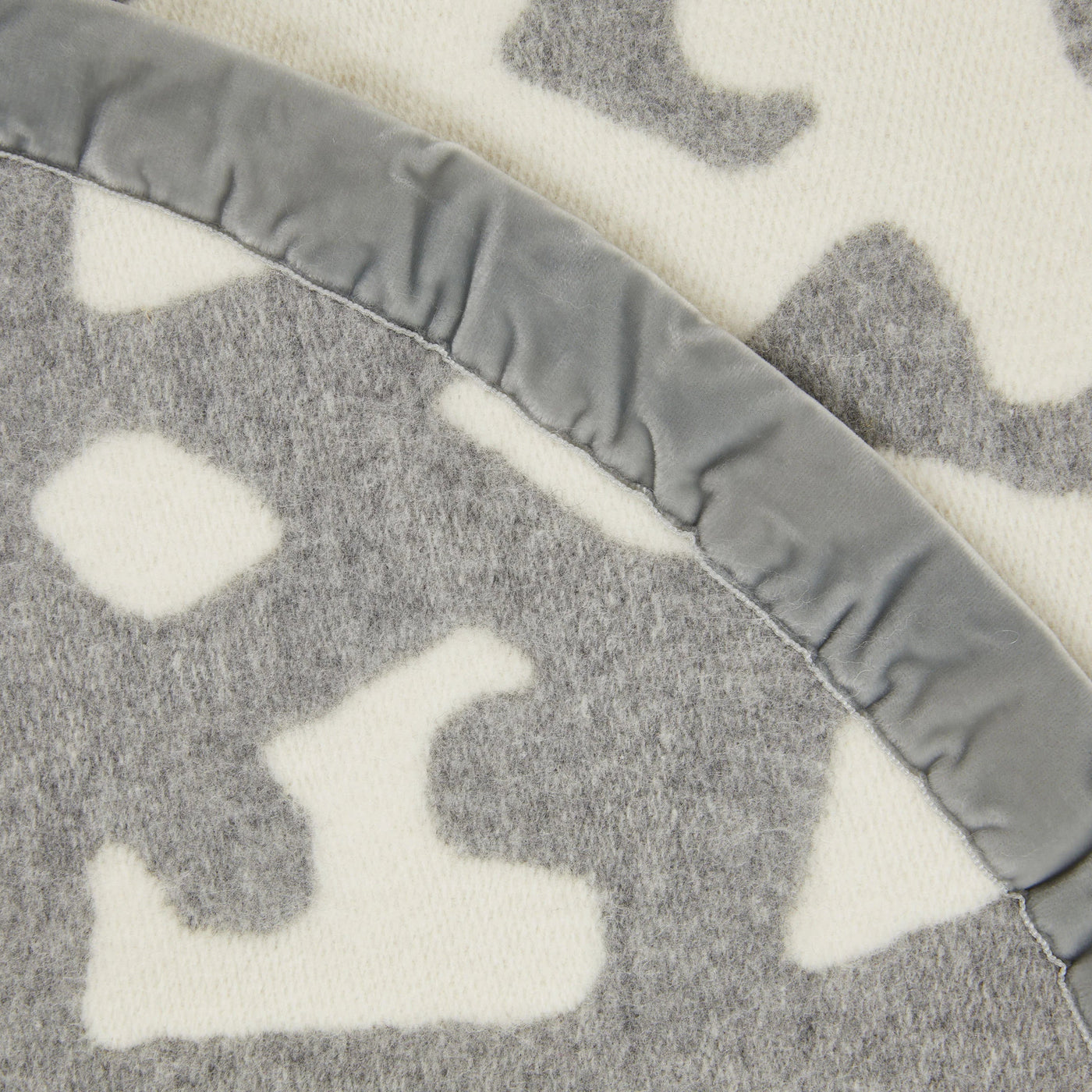 Close-up of Lanerossi Tribal blanket's grey velvet binding edge and ivory leopard pattern.