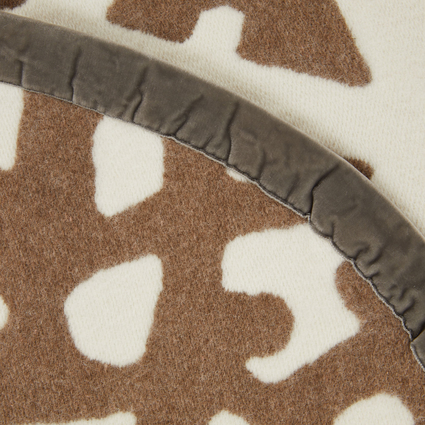 Close-up of Lanerossi Tribal blanket's grey velvet trim against camel and ivory pattern.