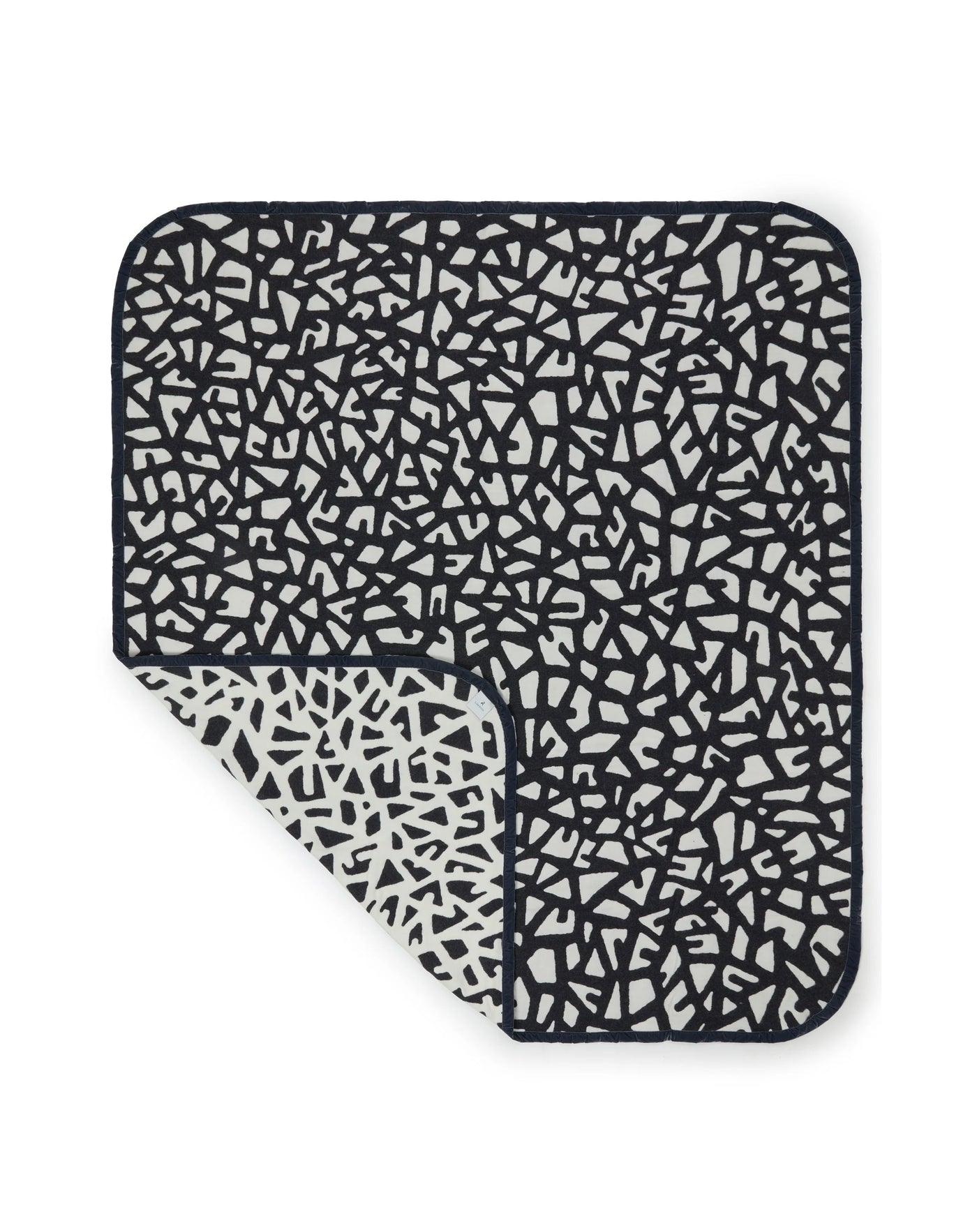 Lanerossi Tribal blanket corner folded back, revealing ivory reverse of black geometric print.