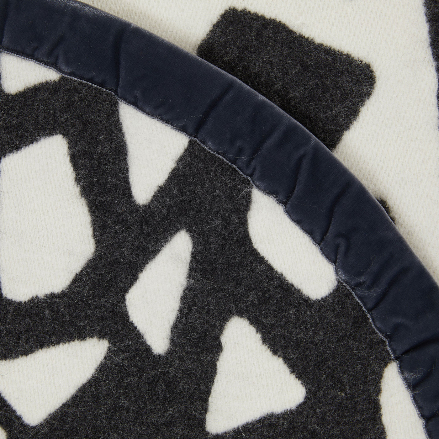 Close-up of Lanerossi Tribal blanket navy velvet trim against charcoal and ivory wool pattern.
