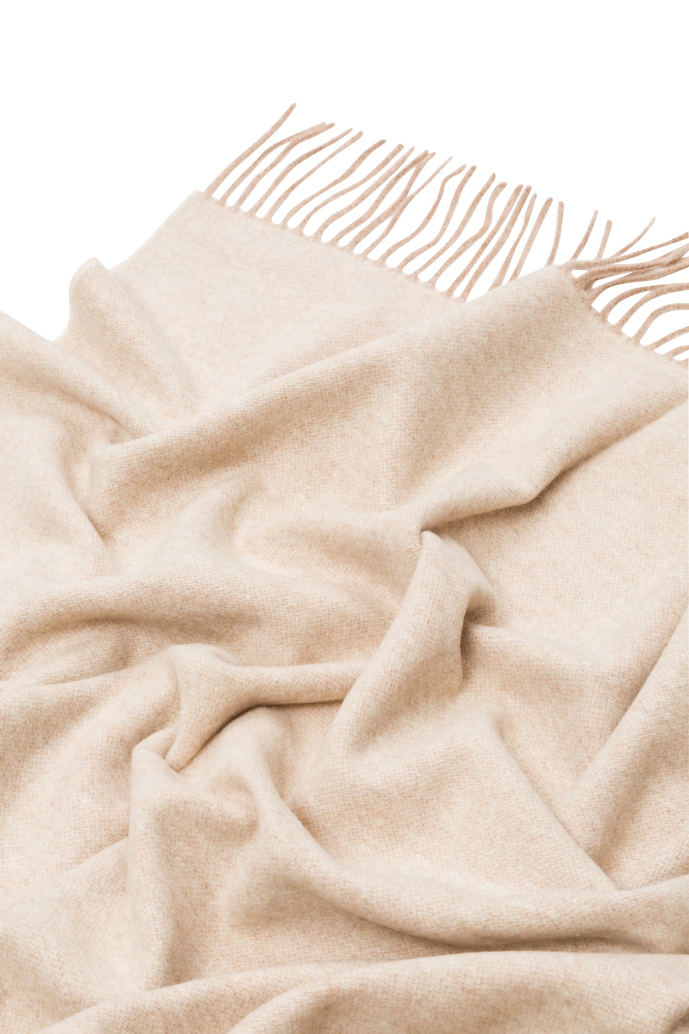 Draped ivory wool throw with knotted fringe trim, showing soft folds and woven texture.