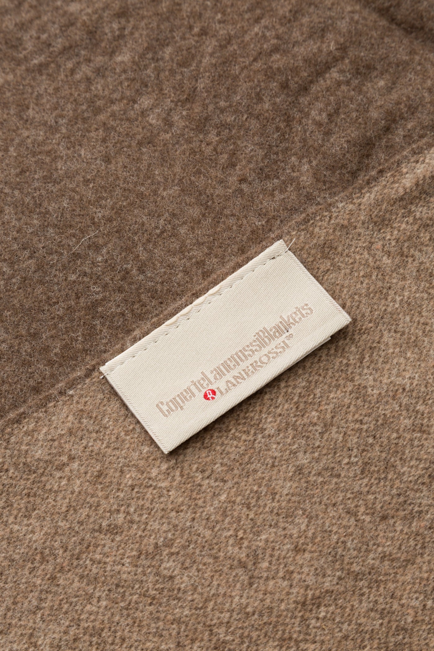 Close-up of Lanerossi label stitched onto a taupe wool throw surface.