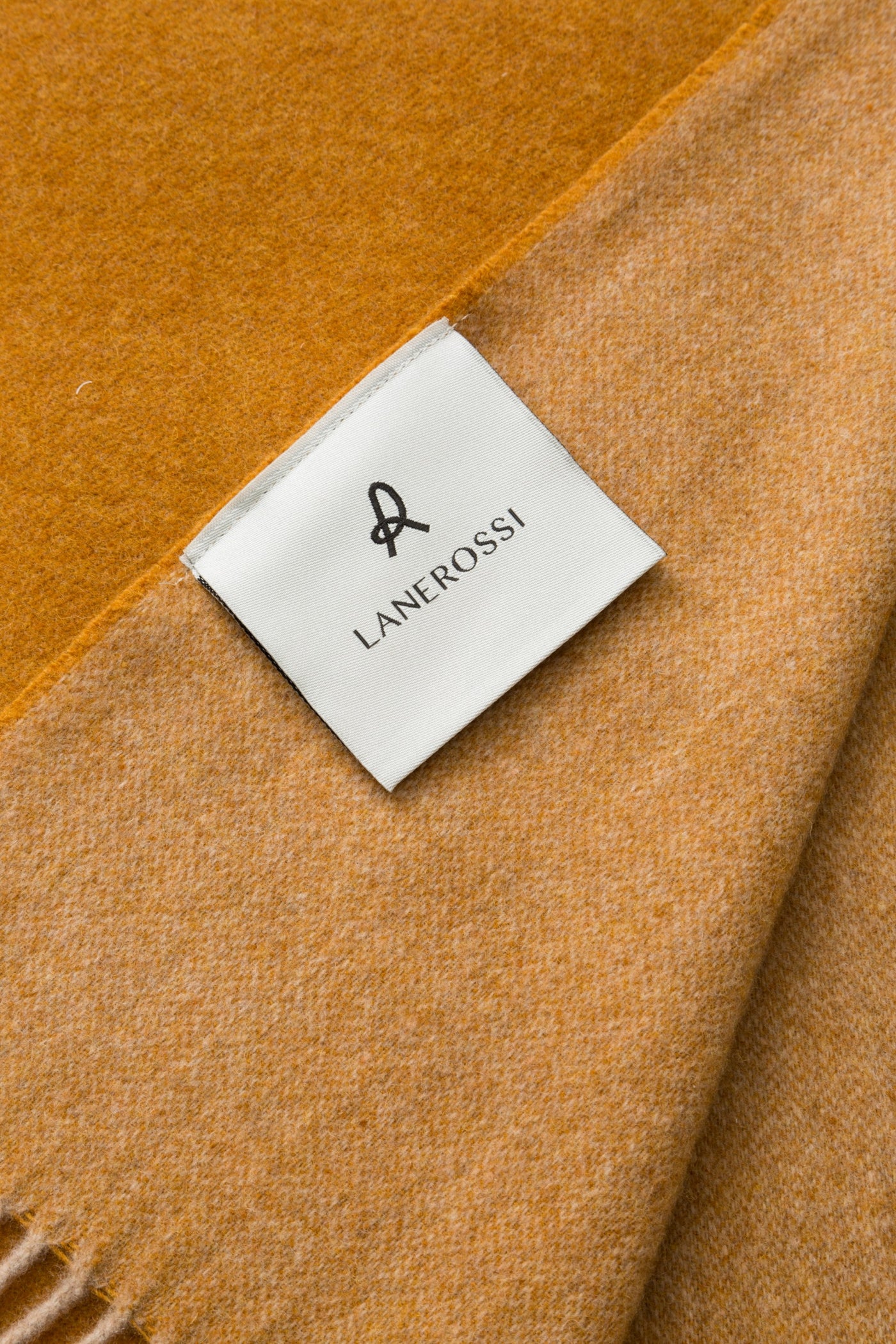 Close-up of Lanerossi Ulisse throw label on saffron and amber wool fabric.