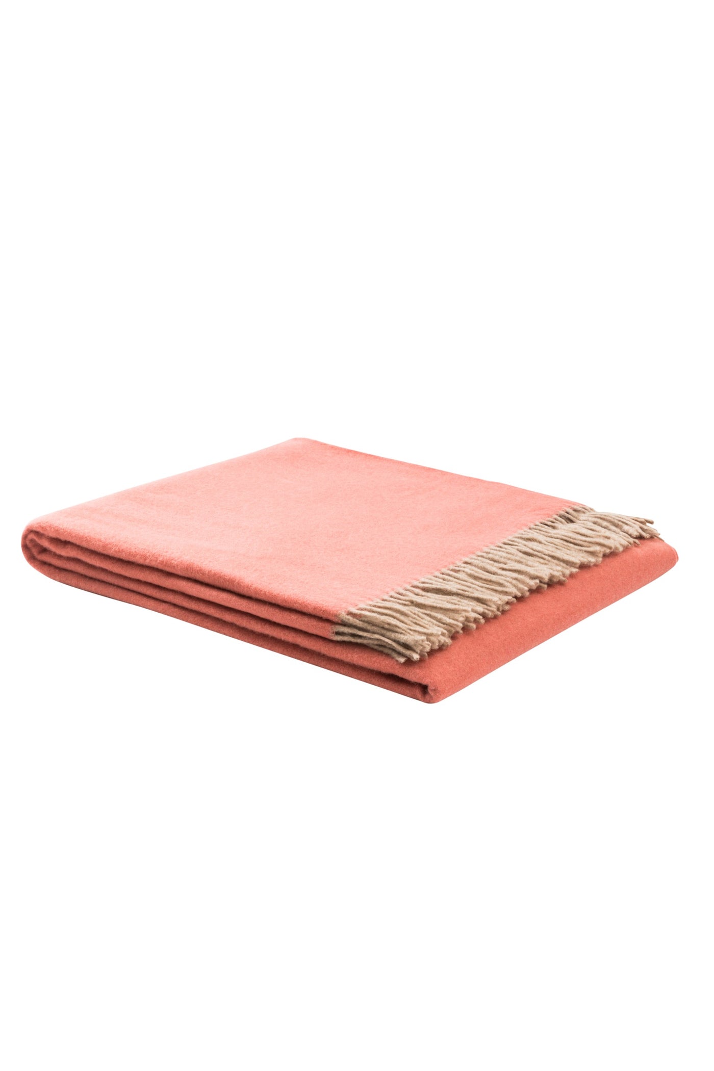 Folded coral throw with contrasting natural fringe trim, angled view.