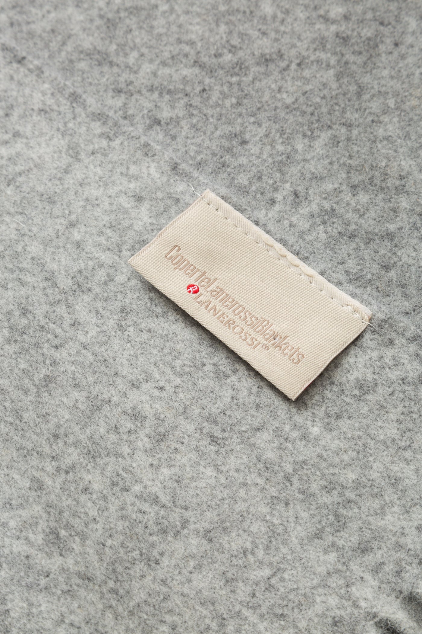 Close-up of Lanerossi label stitched onto heathered grey wool throw fabric.
