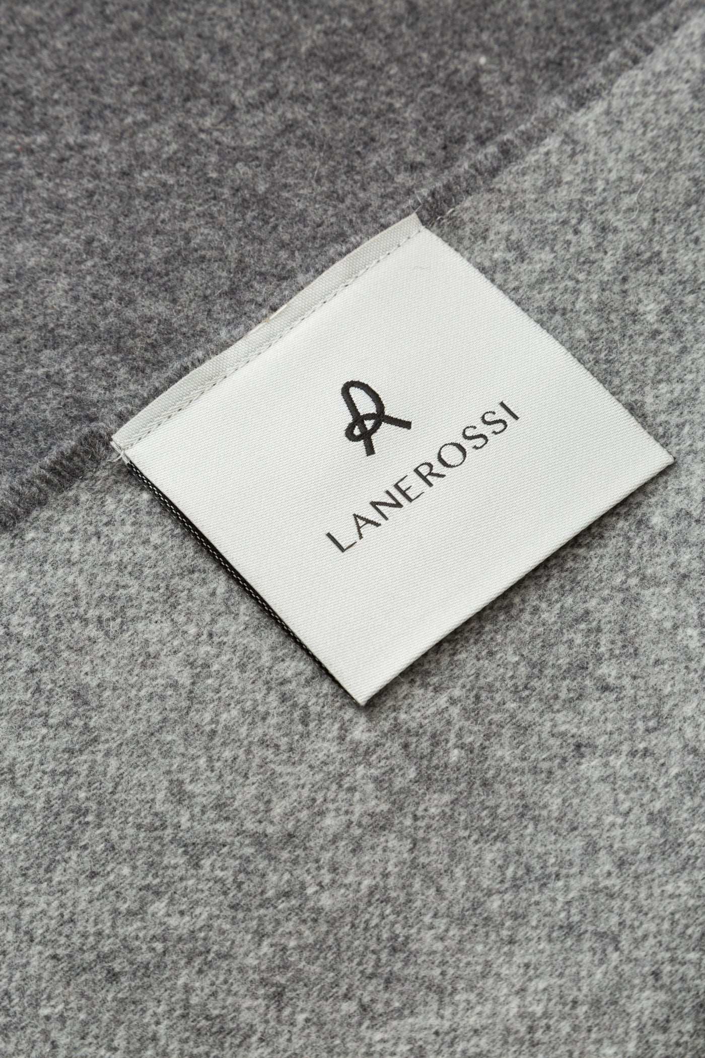 Close-up of Lanerossi woven label on grey Ulisse throw fabric.