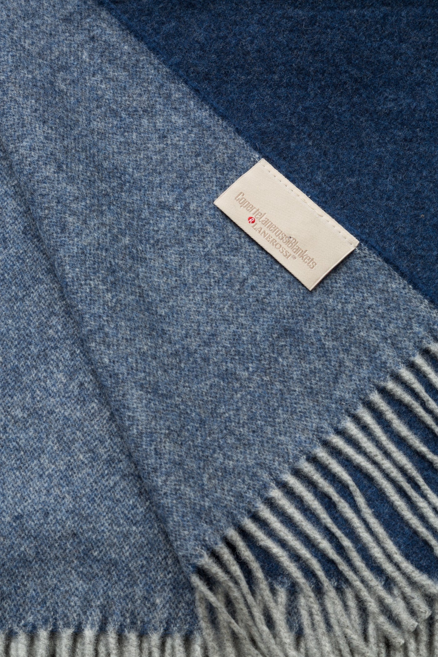 Close-up of Lanerossi Ulisse throw fringe and woven label, two-tone denim blue colorblock detail.