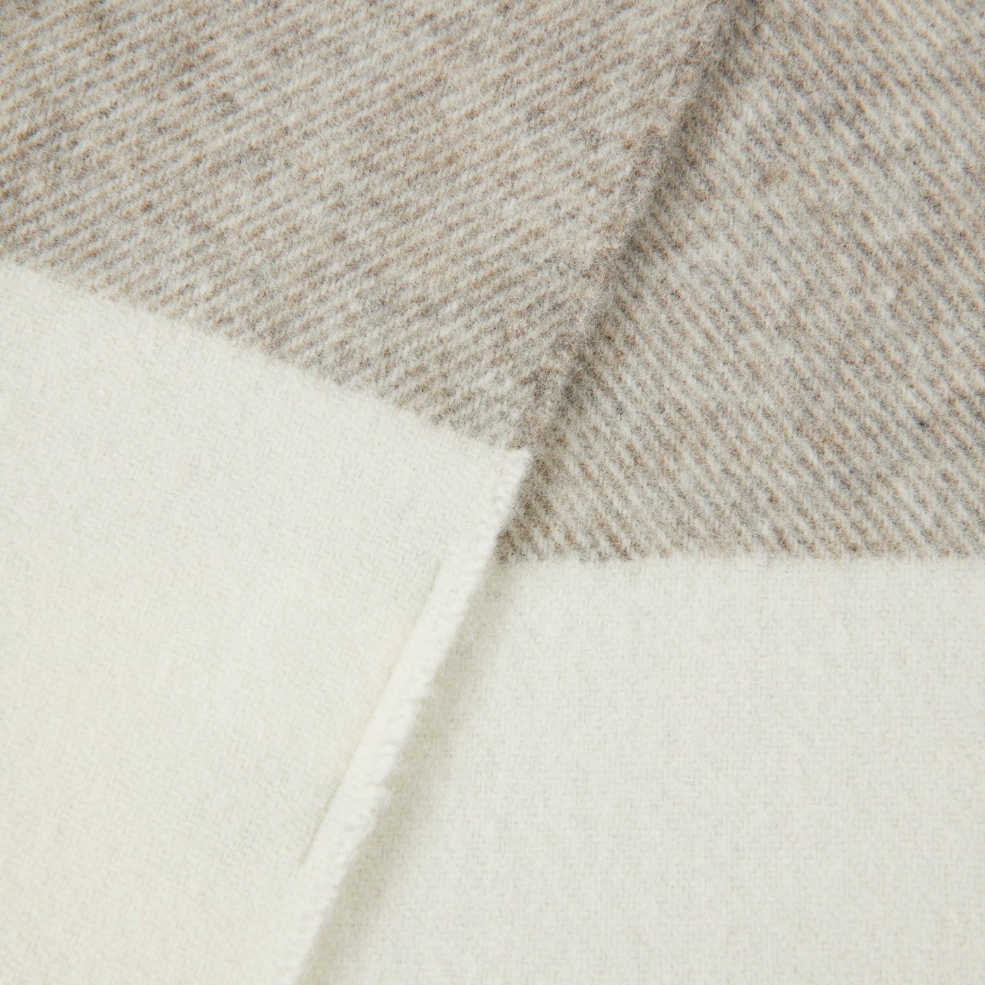 Close-up of folded ivory and taupe check wool throw, showing reverse side and diagonal weave.