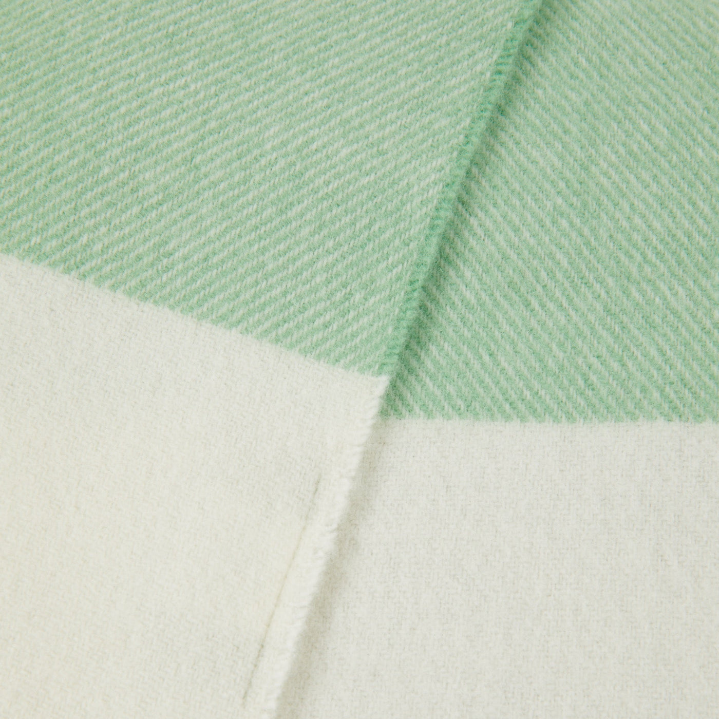 Close-up of Lanerossi Uruguay throw corner, mint and ivory herringbone weave with colour-block border.