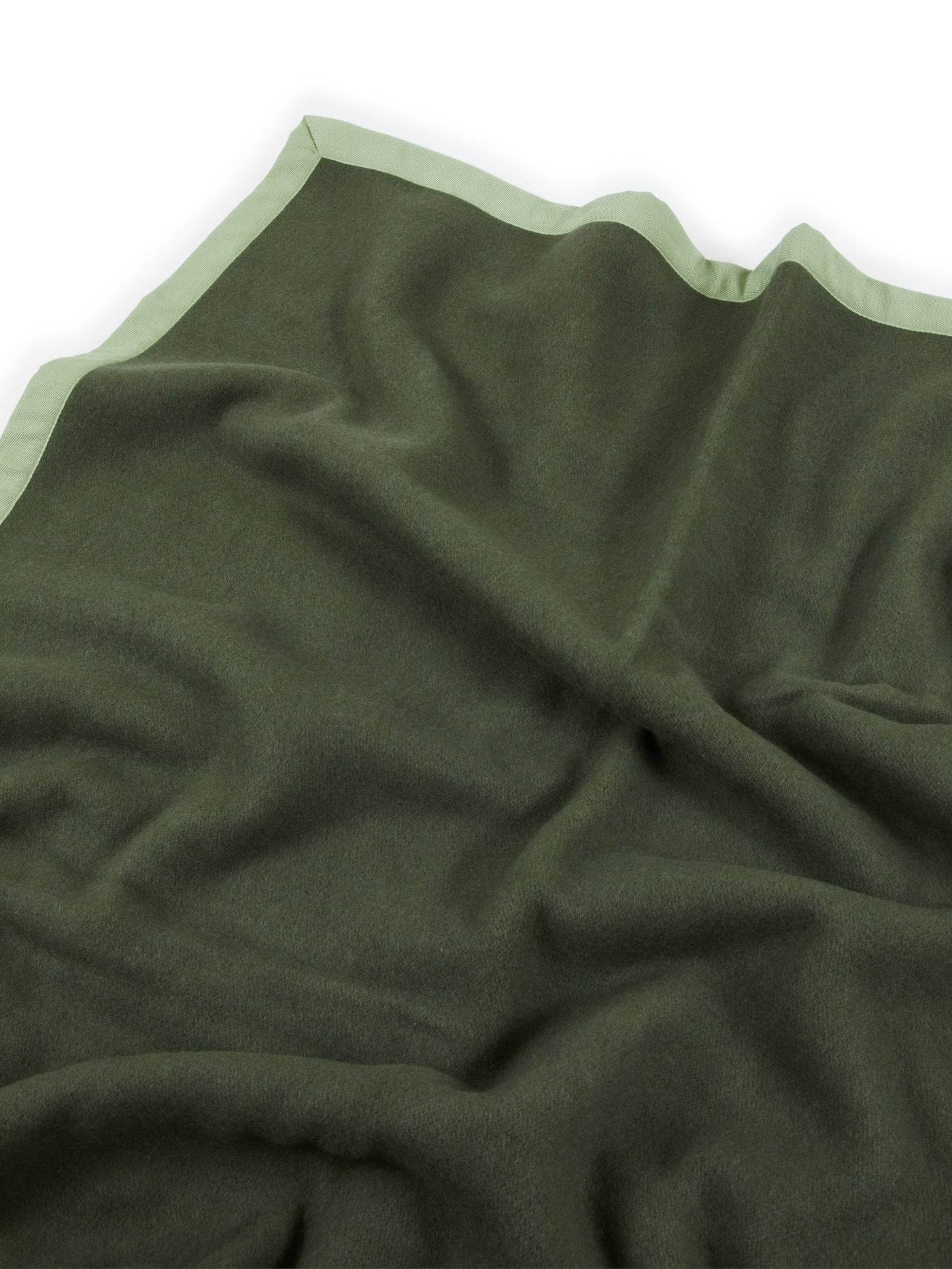 Close-up of Lanerossi Uruguay blanket in forest green with sage contrast trim edge.