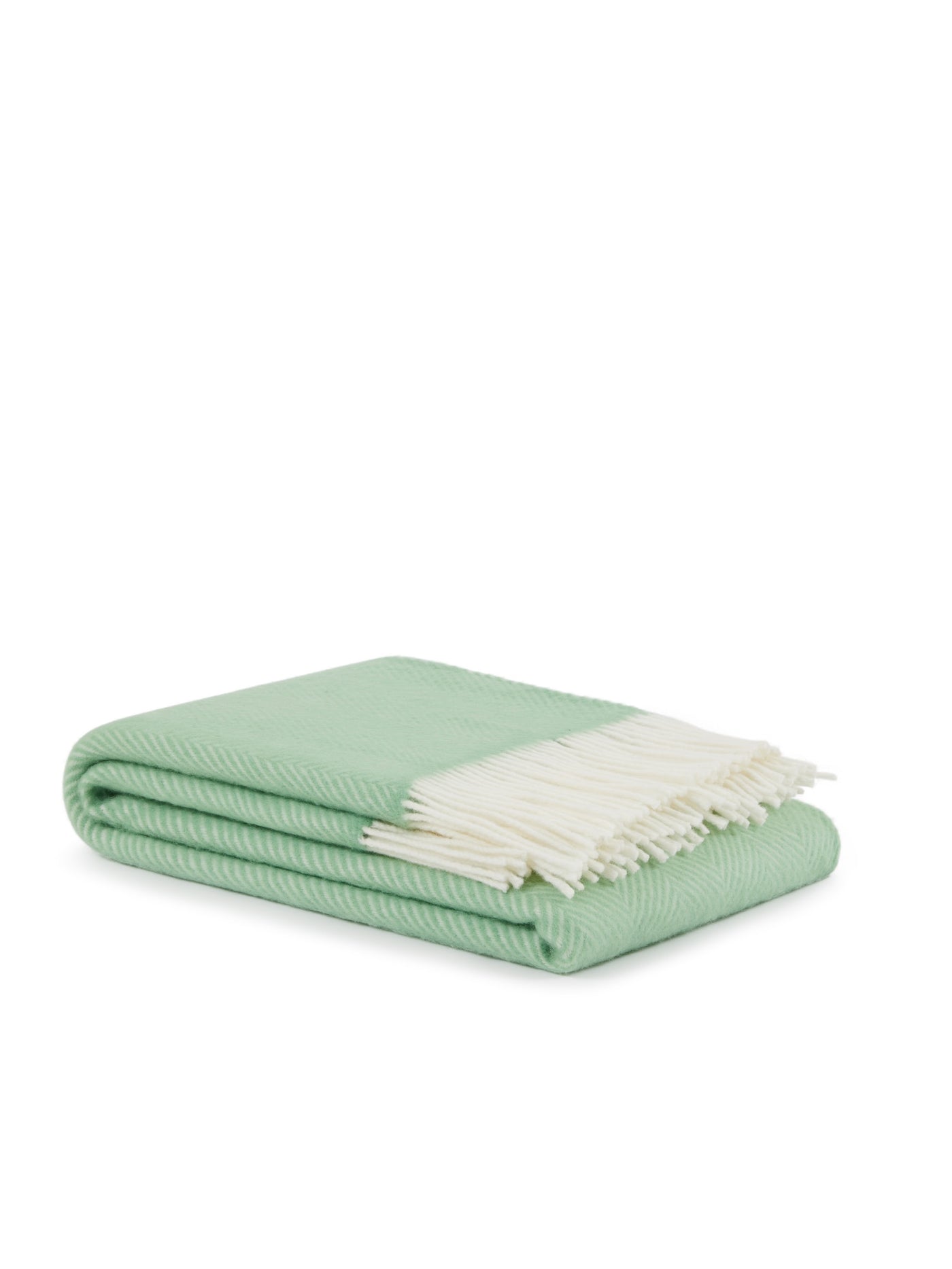 Folded mint green herringbone throw with ivory fringe trim, side angle view.