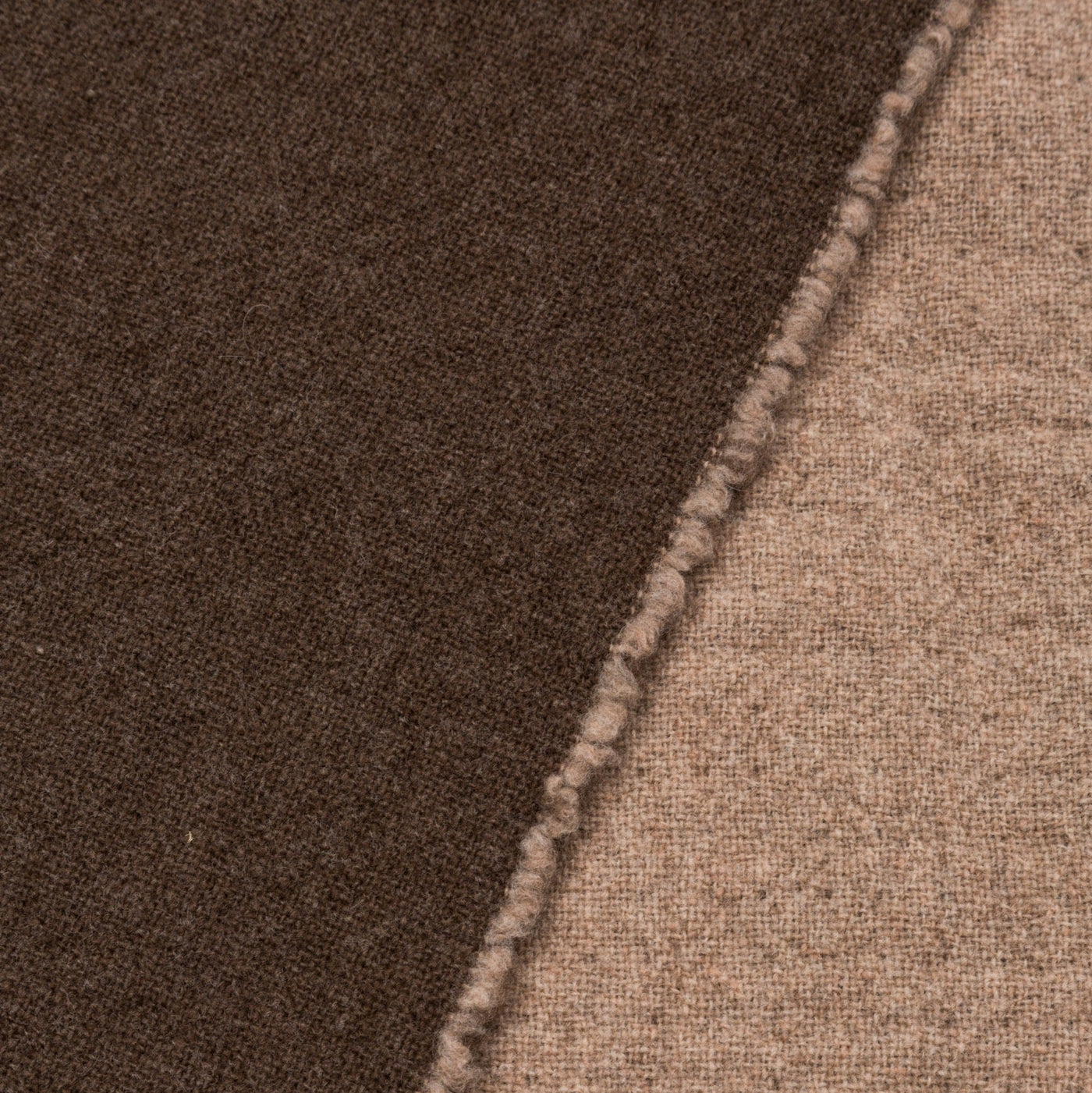 Close-up of blanket seam joining espresso and sand wool faces.