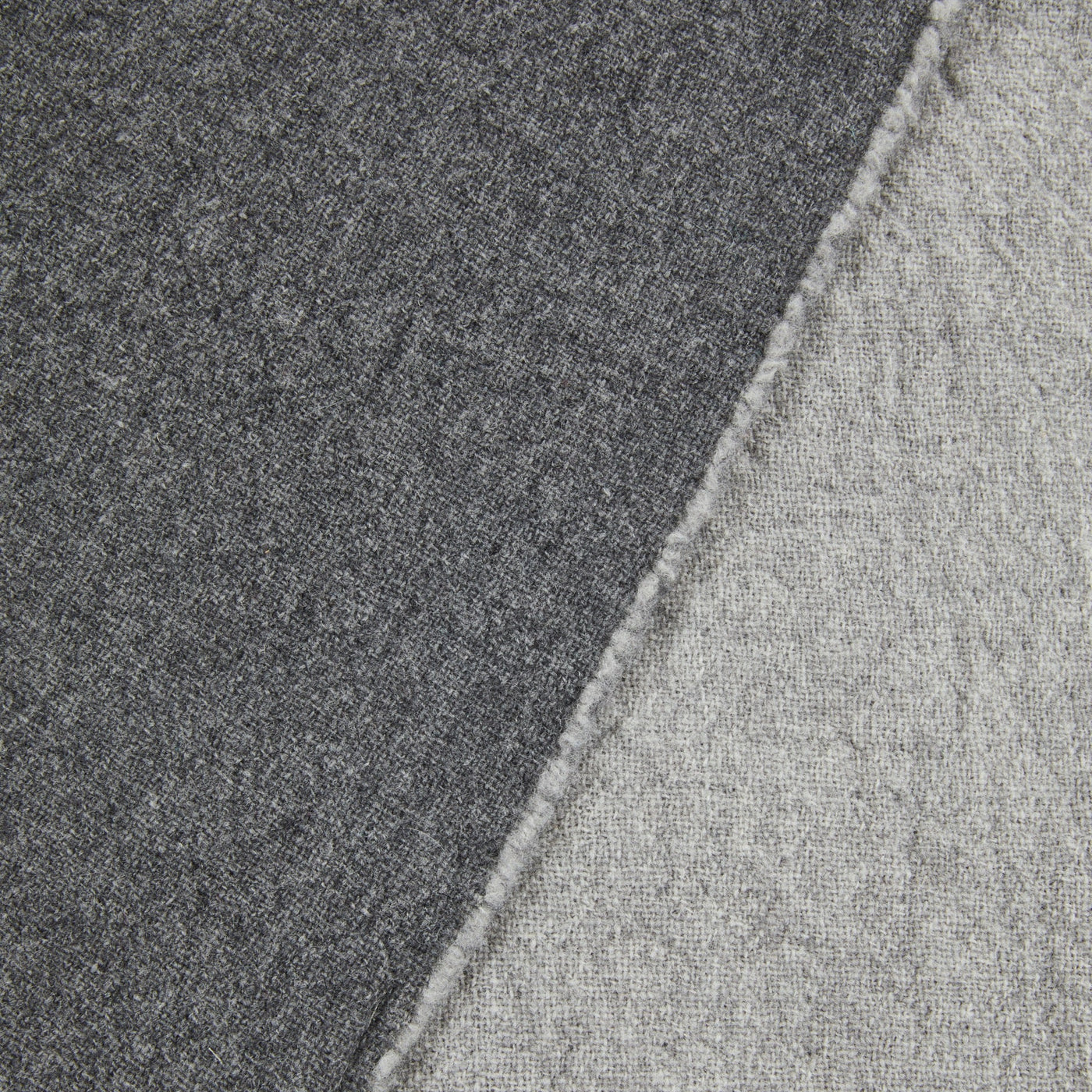 Close-up of charcoal and light grey reversible wool blanket showing contrast seam edge.