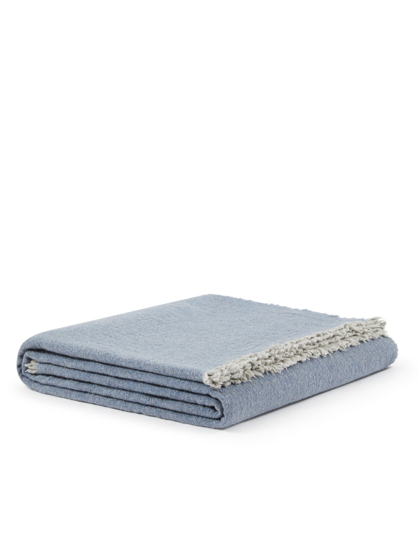 Folded slate blue blanket with ivory fringe trim visible along one edge.