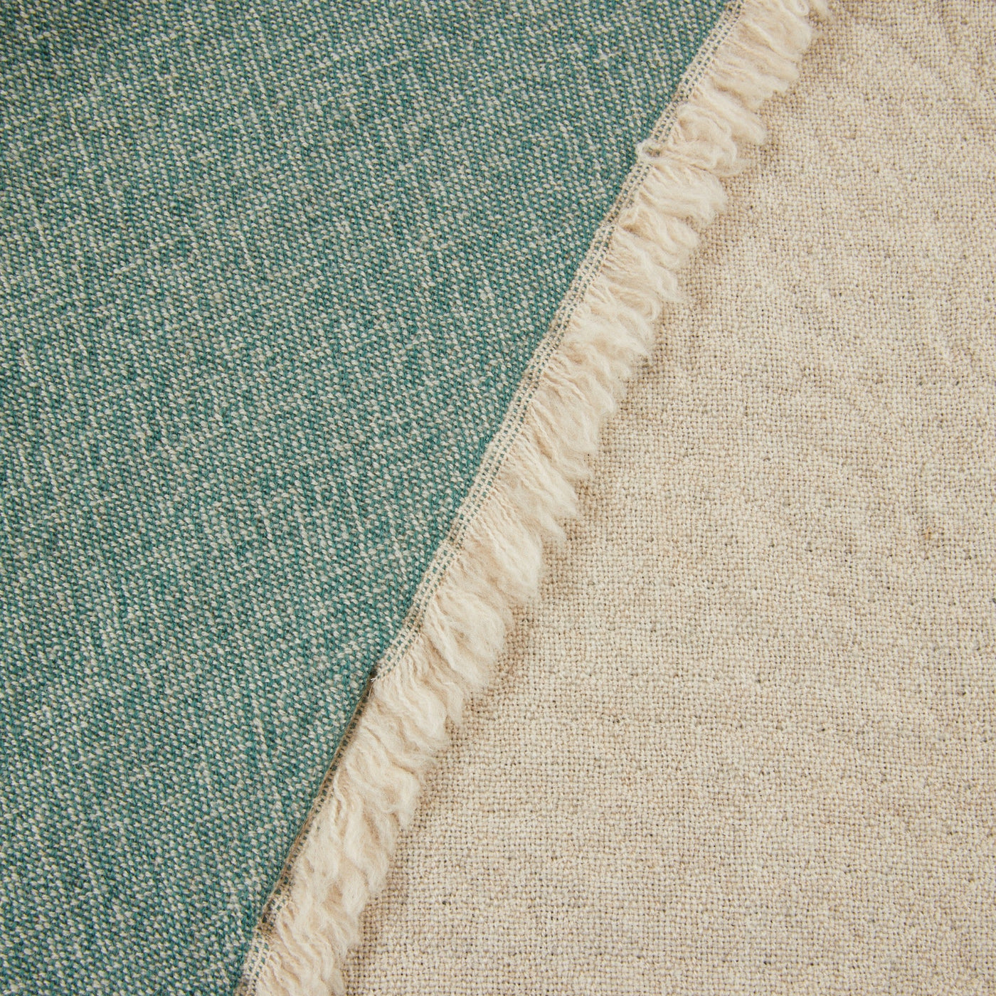 Close-up of Lanerossi Zebio throw's fringed edge, teal and natural linen reverse sides visible.