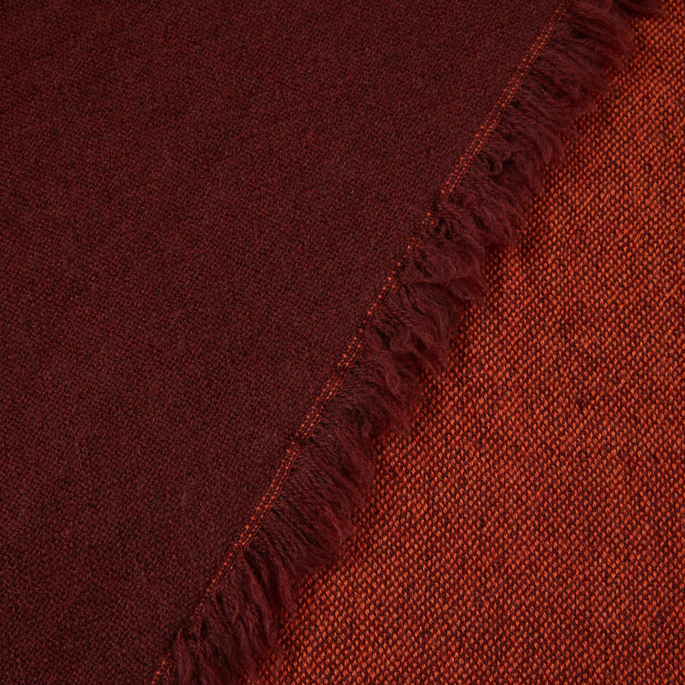 Close-up of Lanerossi Zebio throw showing reversible ruby and burnt orange weave with fringe edge.