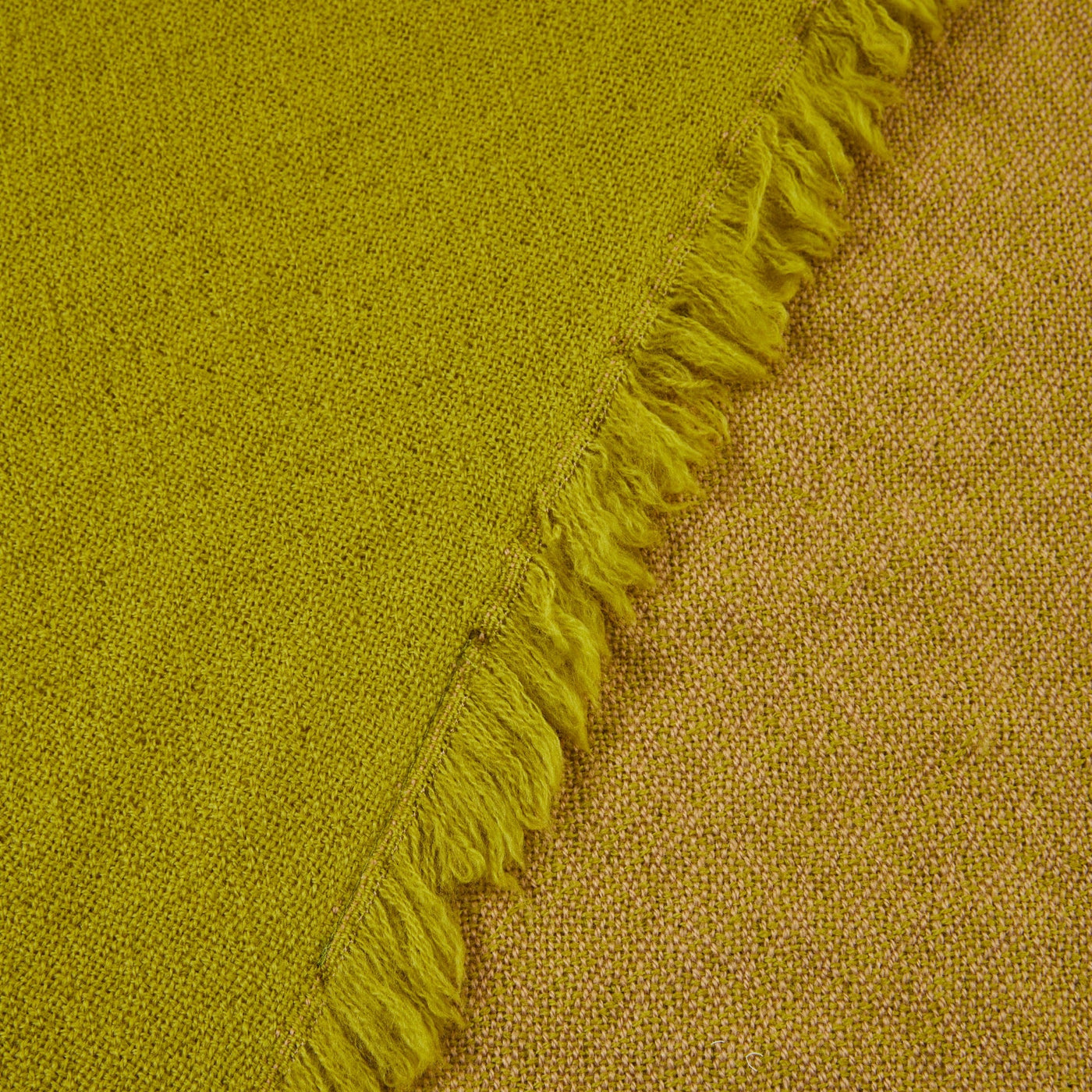 Close-up of chartreuse woven throw showing fringed edge and contrast reverse side.
