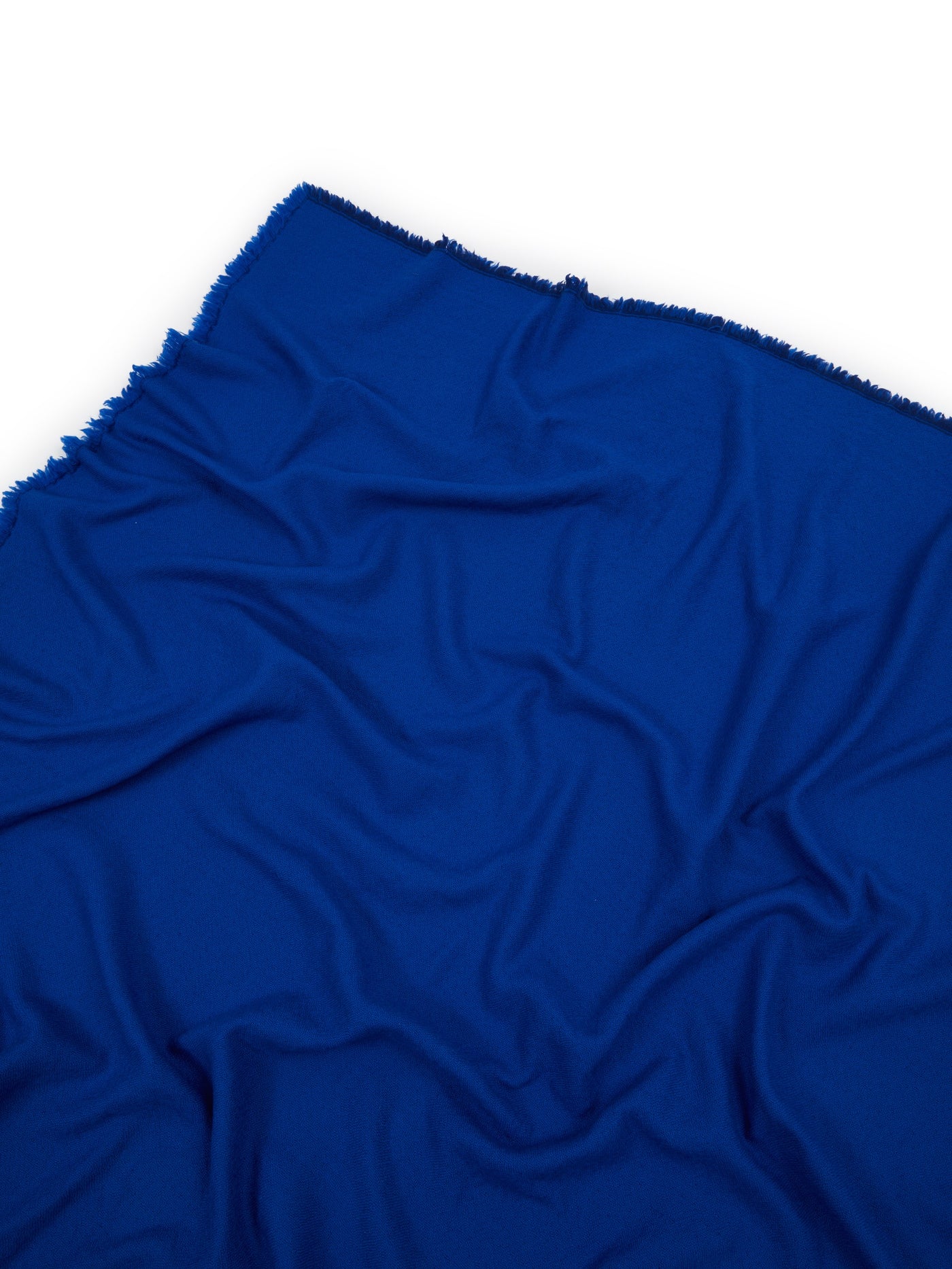 Cobalt blue throw with fringed edge, draped to show soft fabric drape and texture.