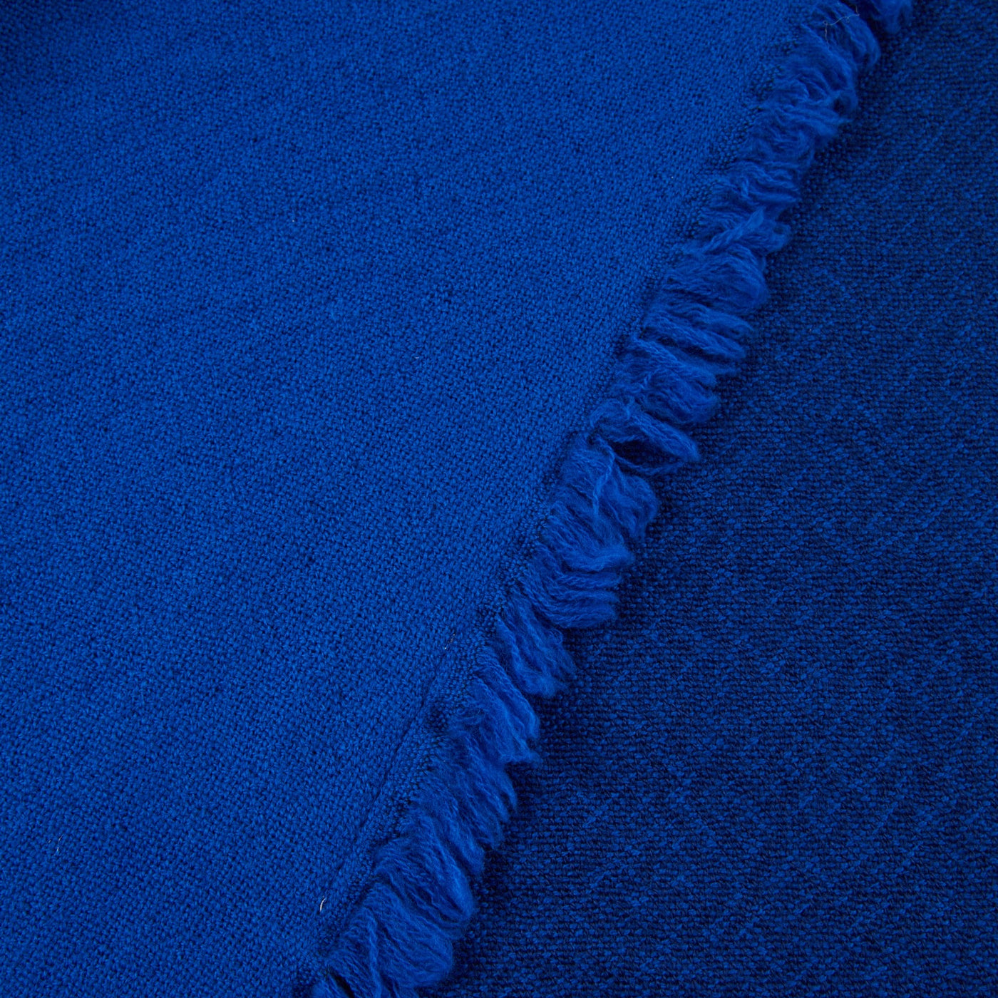 Close-up of cobalt blue woven throw's fringed edge detail.