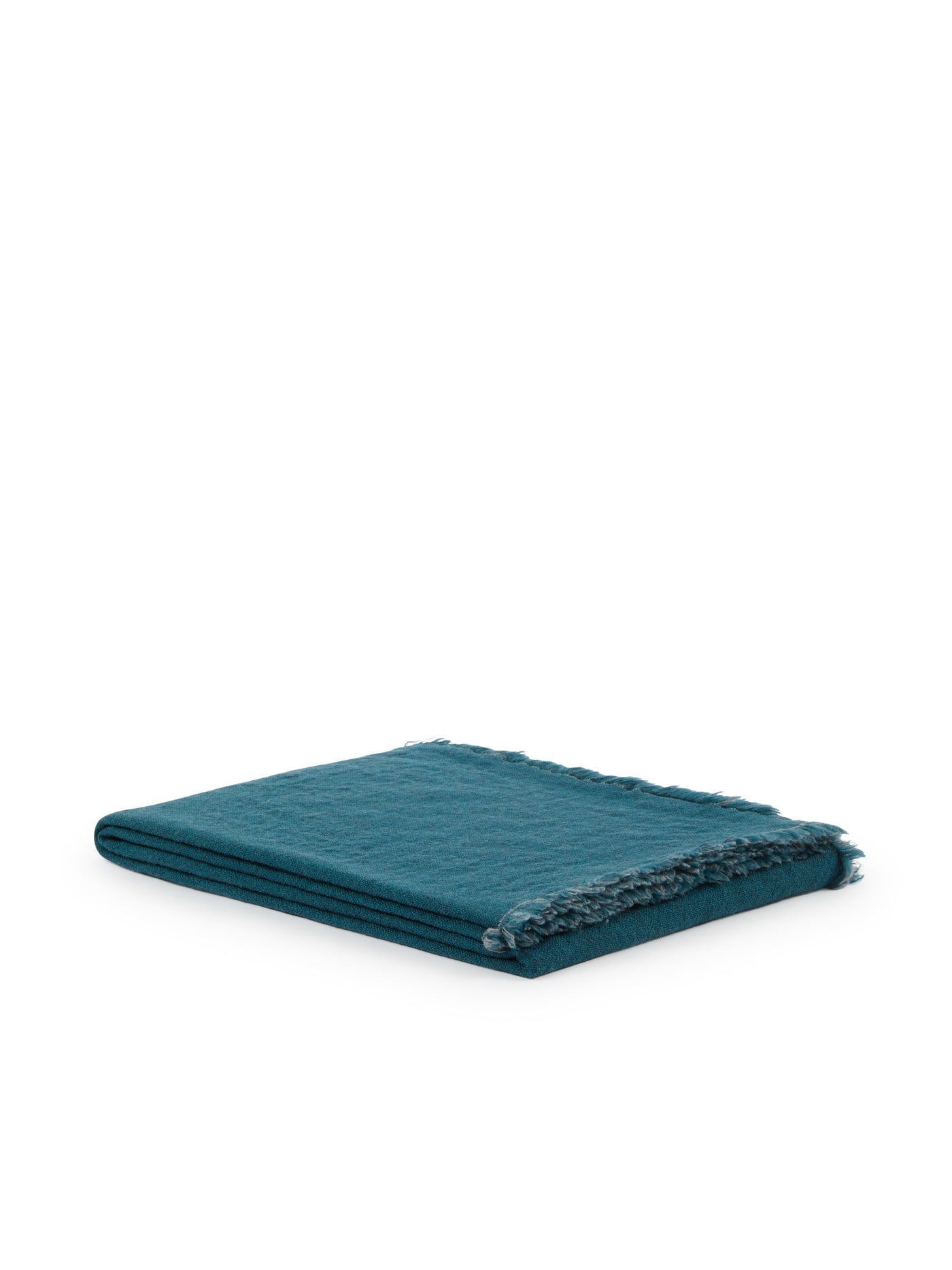 Teal woven throw folded flat, showing frayed fringe edge detail.